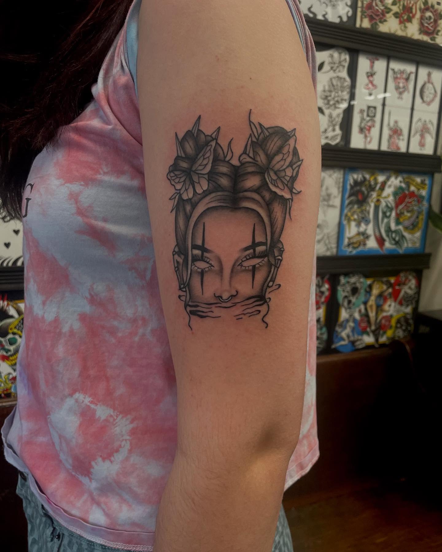 Woman's face with flowers black and grey tattoo on the forearm by Kylee langford 🧿