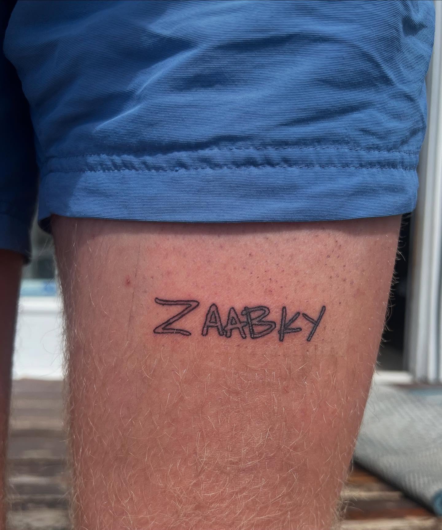 Zaabky lettering script tattoo on the thigh by Kylee Snow