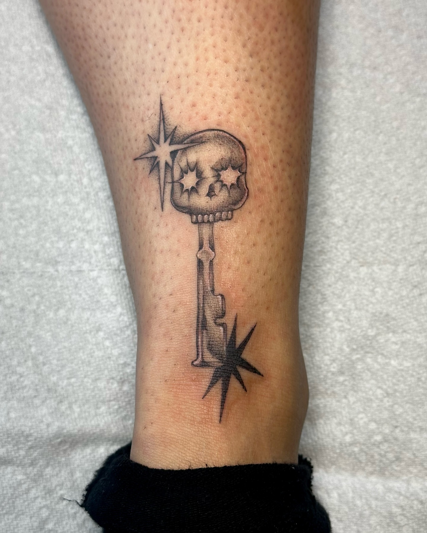 Key with skull black and grey tattoo on the forearm by cora cupid