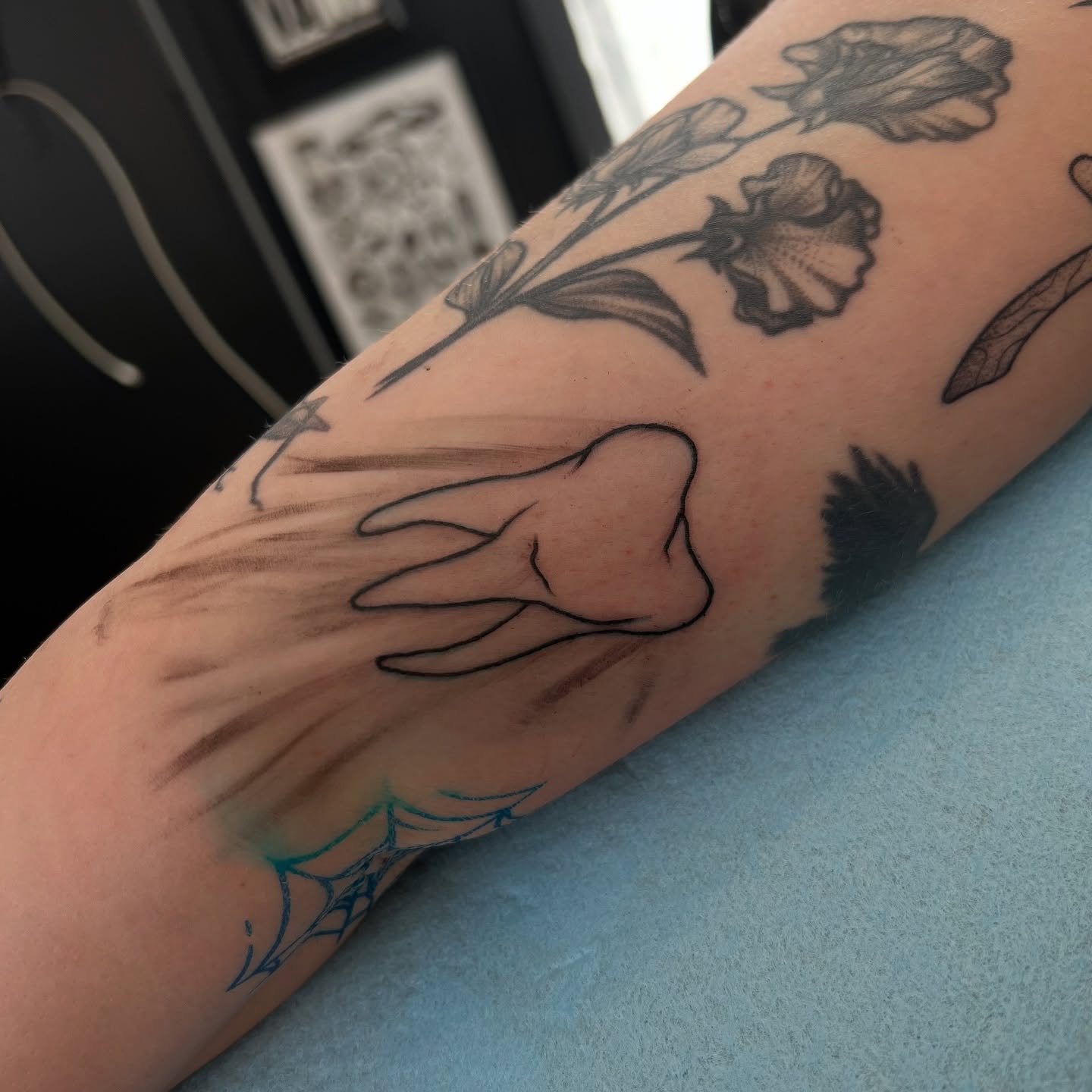 Flowers and hand black and grey tattoo on the forearm by Dom