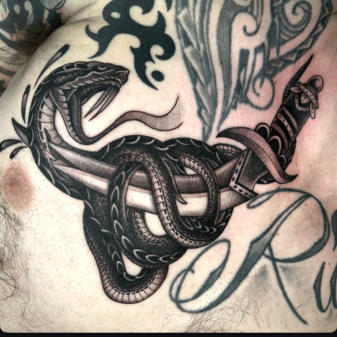 Snake and dagger American traditional tattoo on the chest by Pat Moser