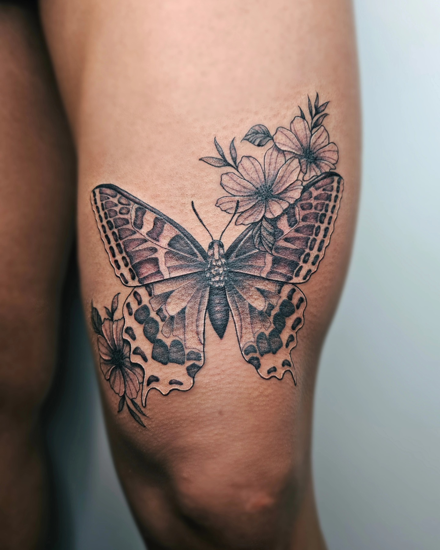 Butterfly and flowers black and grey tattoo on the thigh by TaylorLeighShermanTattoos OFFICIAL