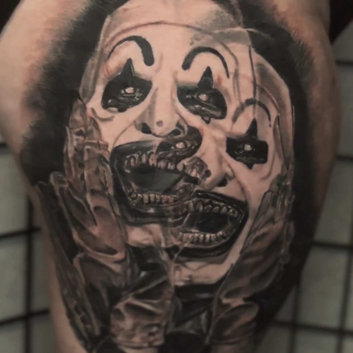 Clown face realism tattoo on the upper arm by C.J. Rued