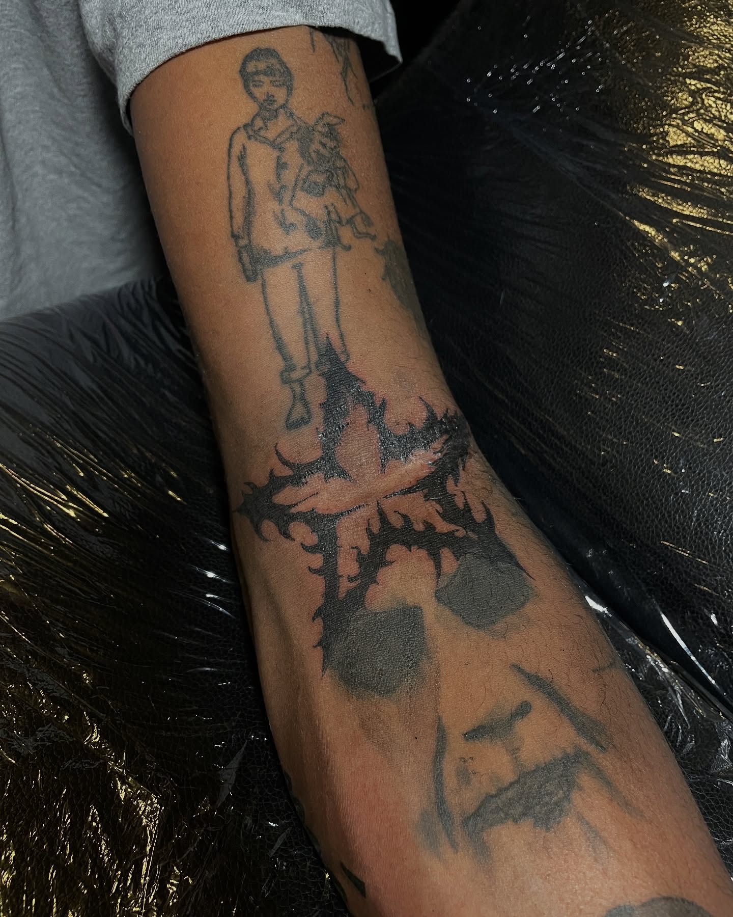Man holding child black and grey tattoo on the forearm by ɴᴏᴍᴢ ᴅʏsᴇᴍʙᴏᴅɪᴍᴇɴᴛ