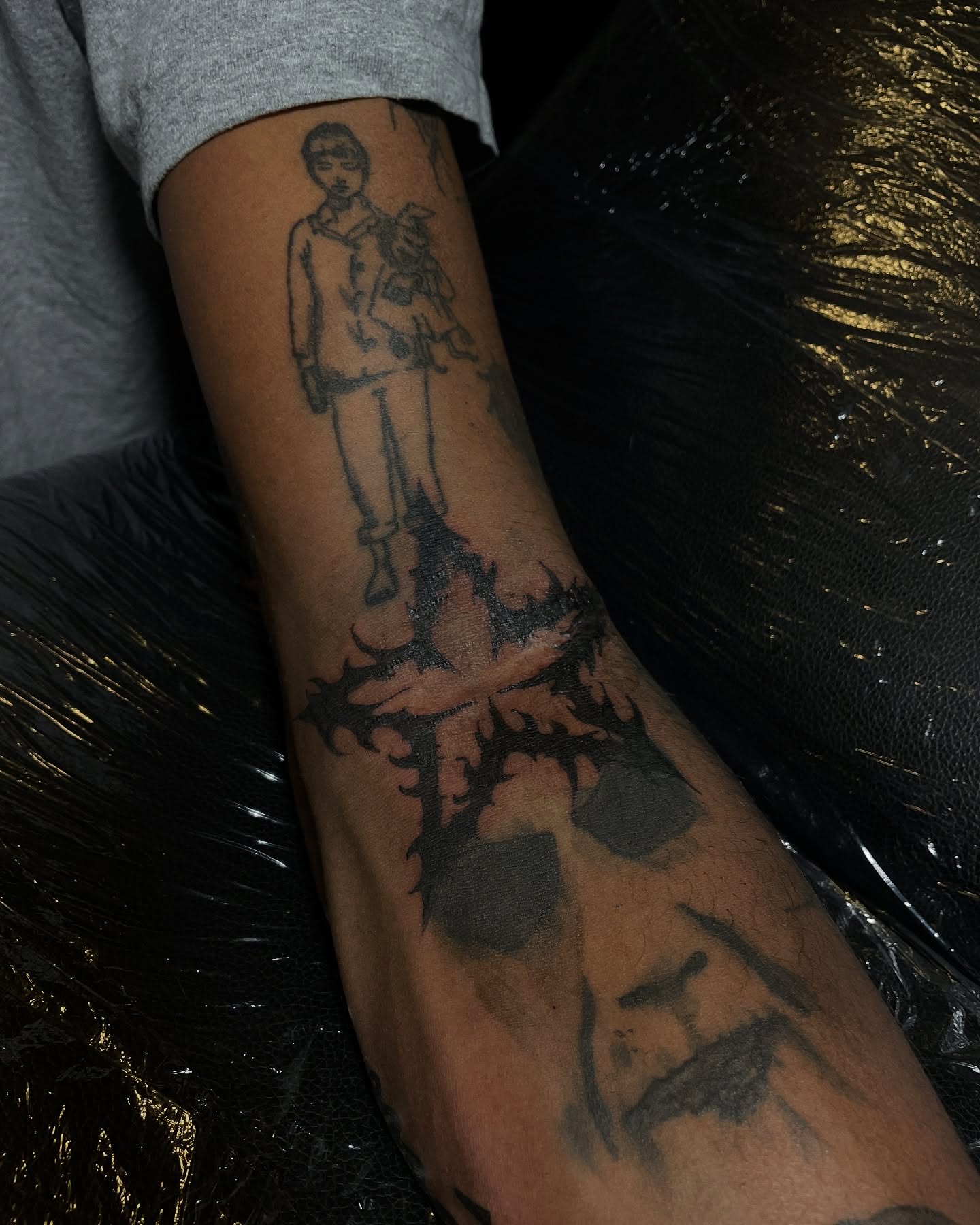 Man standing on cross black and grey tattoo on the forearm by ɴᴏᴍᴢ ᴅʏsᴇᴍʙᴏᴅɪᴍᴇɴᴛ