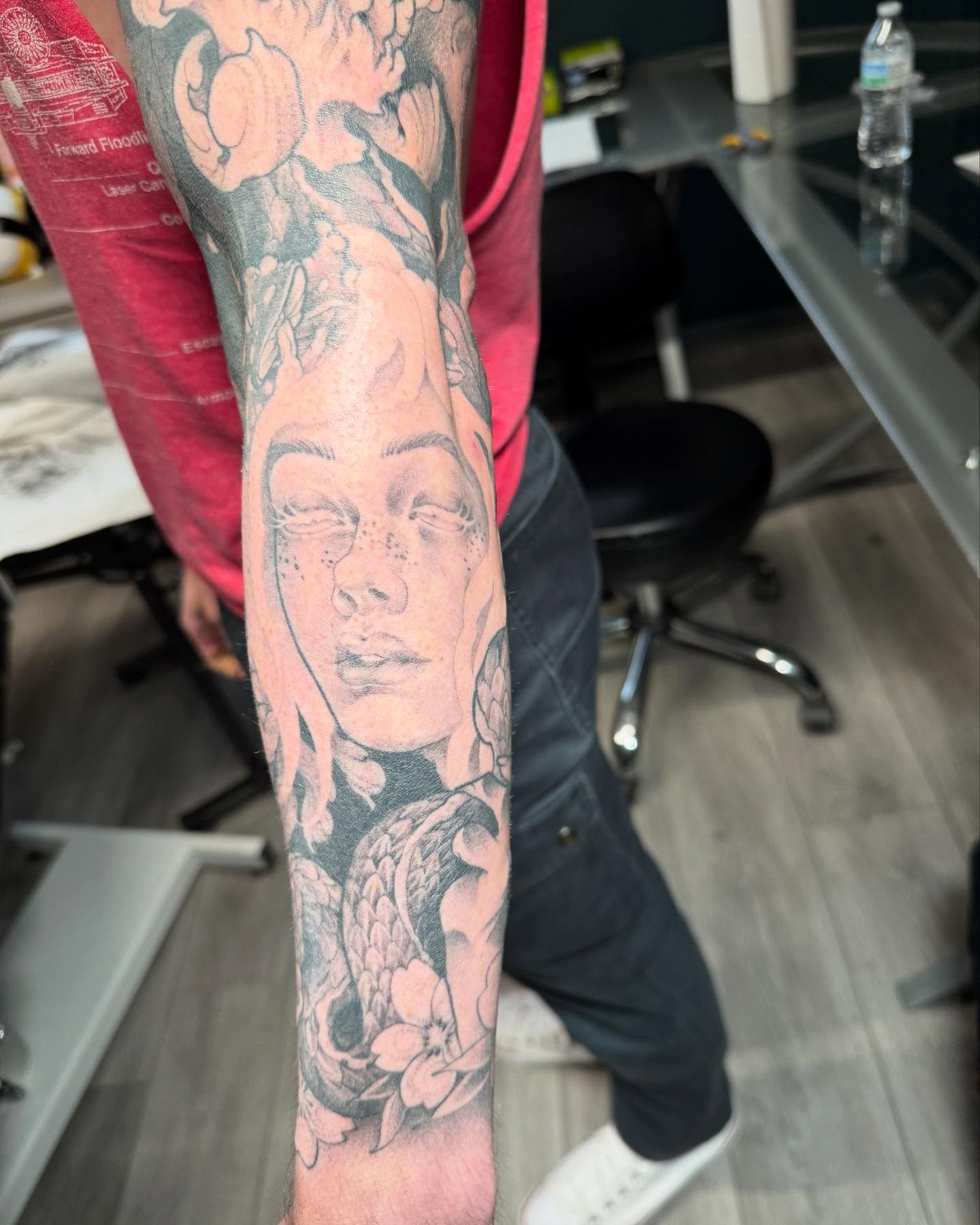 Portrait with floral elements realism tattoo on the forearm by Tayler Beetison