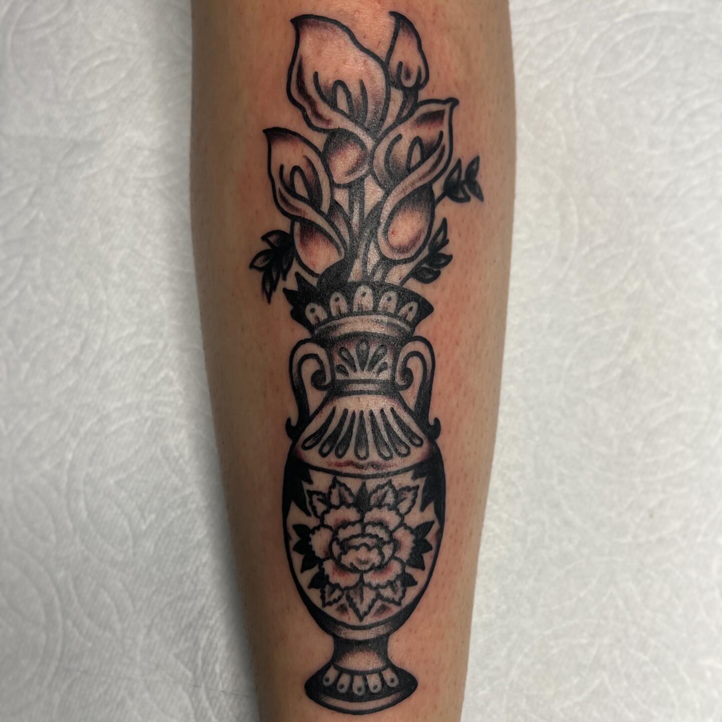 Calla lilies and vase black and grey tattoo on the forearm by Clayton - TRADITIONAL TATTOOS