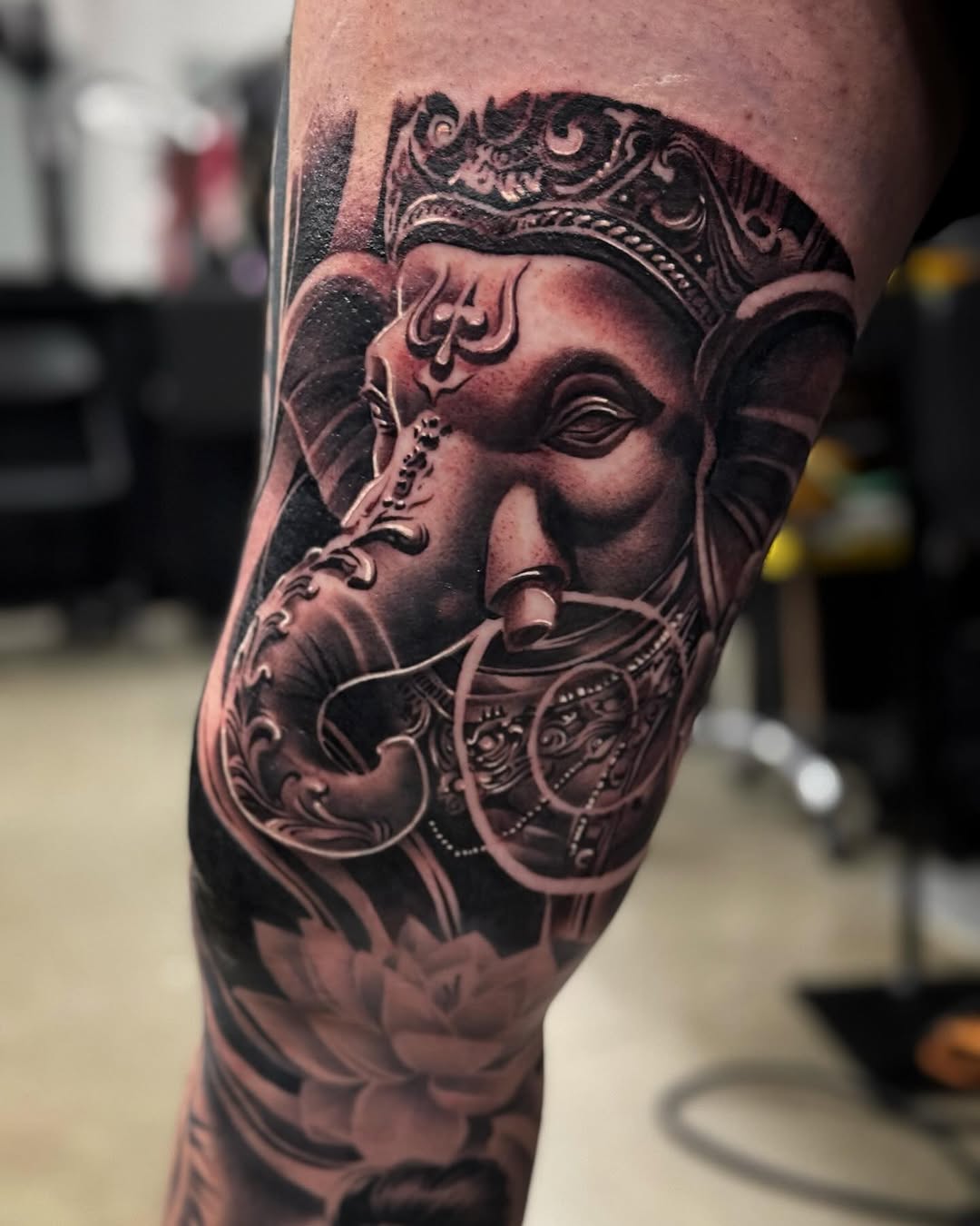 Ganesha with lotus flowers realism tattoo on the forearm by Derek Hutchison, Des Moines, Iowa