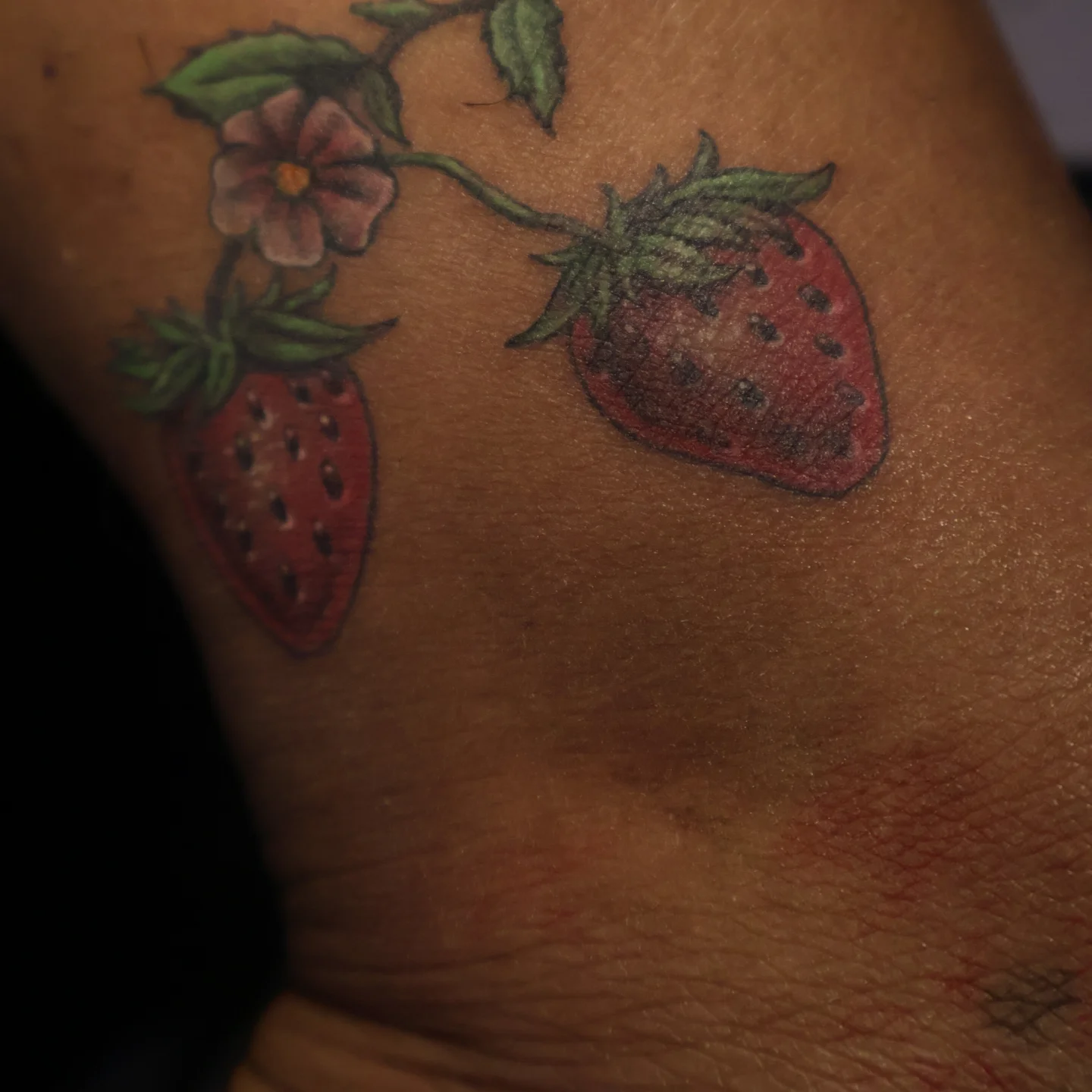 Strawberry and flower realism tattoo on the upper arm by Joc