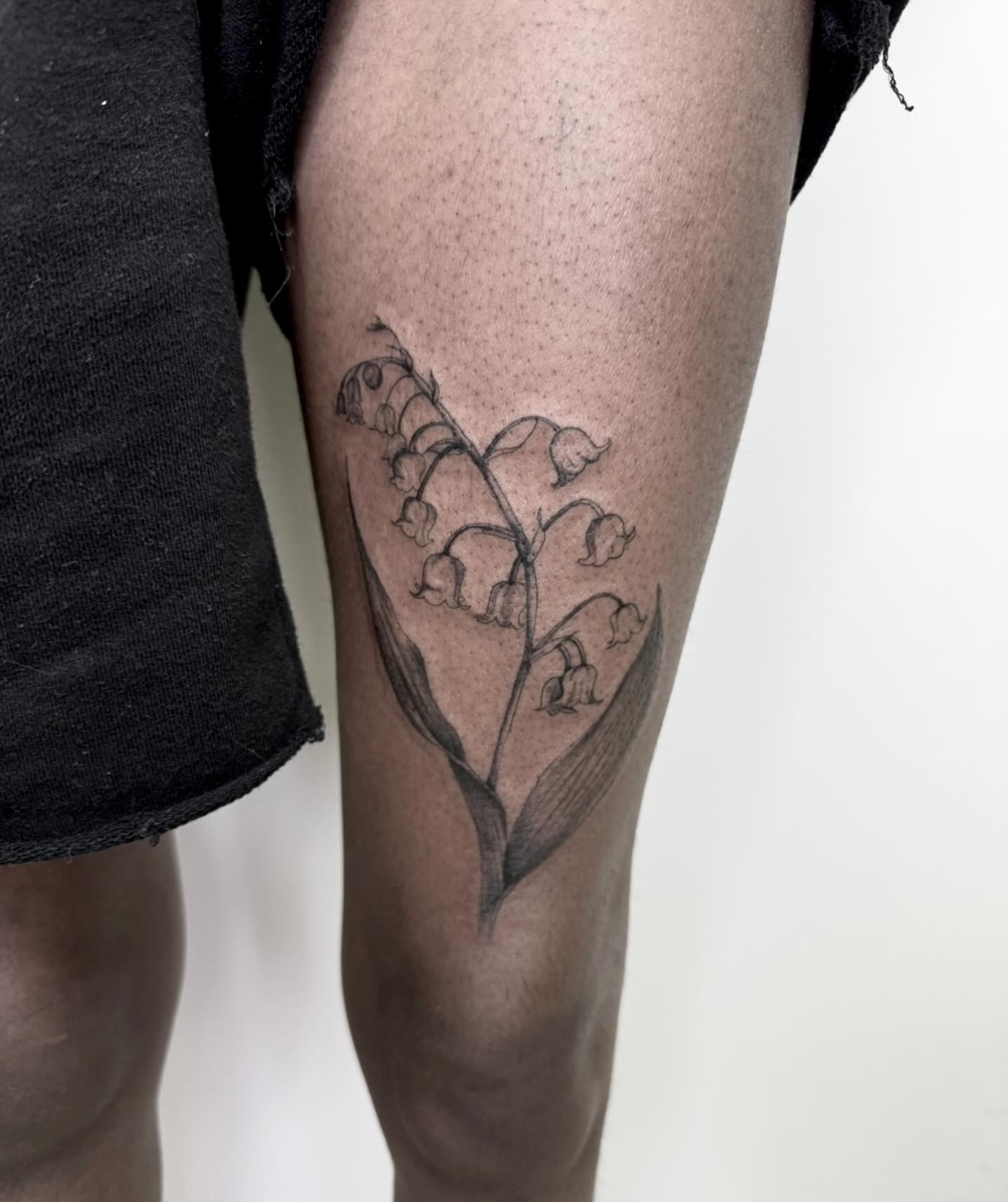 Lily of the valley black and grey tattoo on the thigh by Rachel