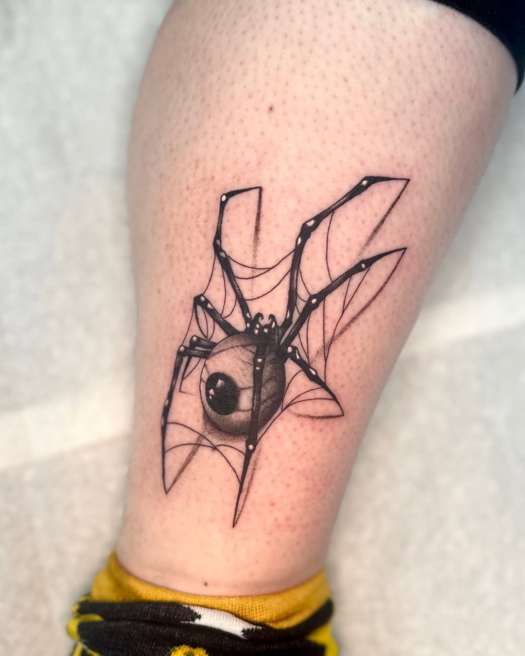 Spider with eyeball sketch tattoo on the thigh by Mandy Kaur