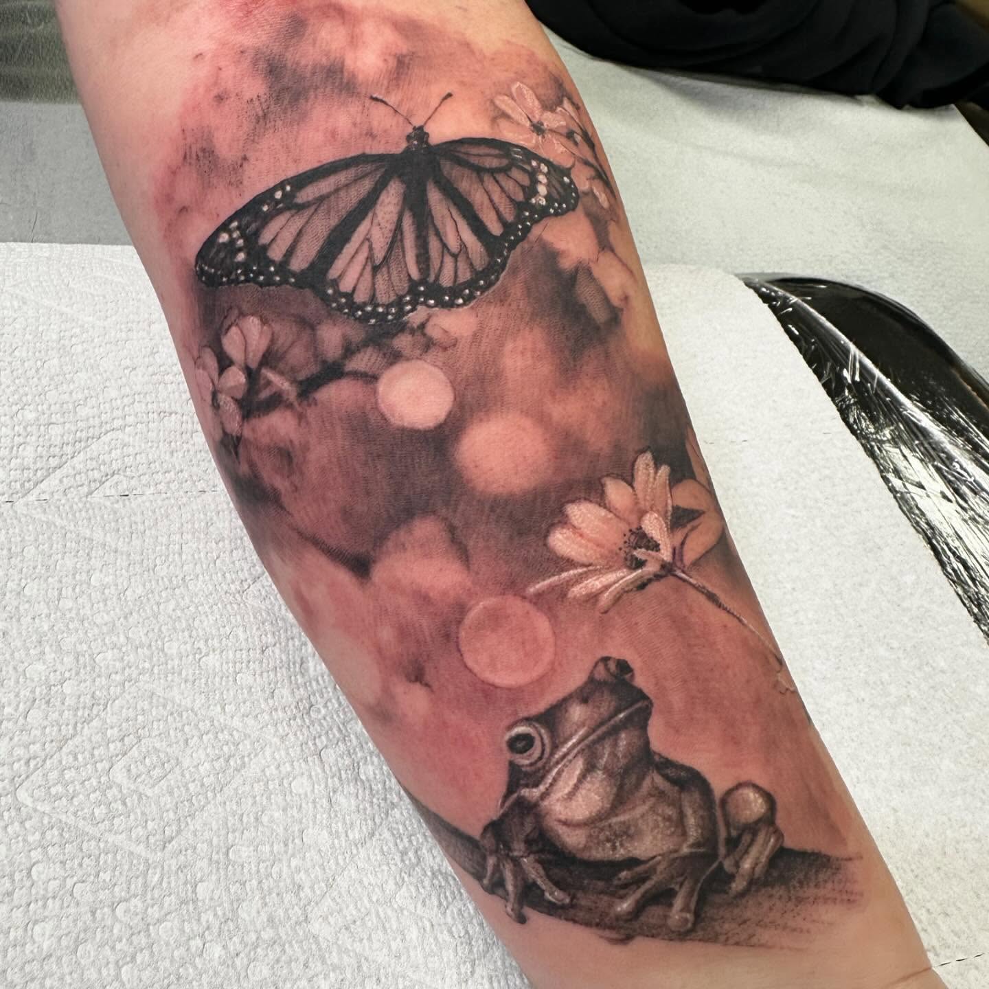 Butterfly, frog, flowers realism tattoo on the forearm by Amber Miracle
