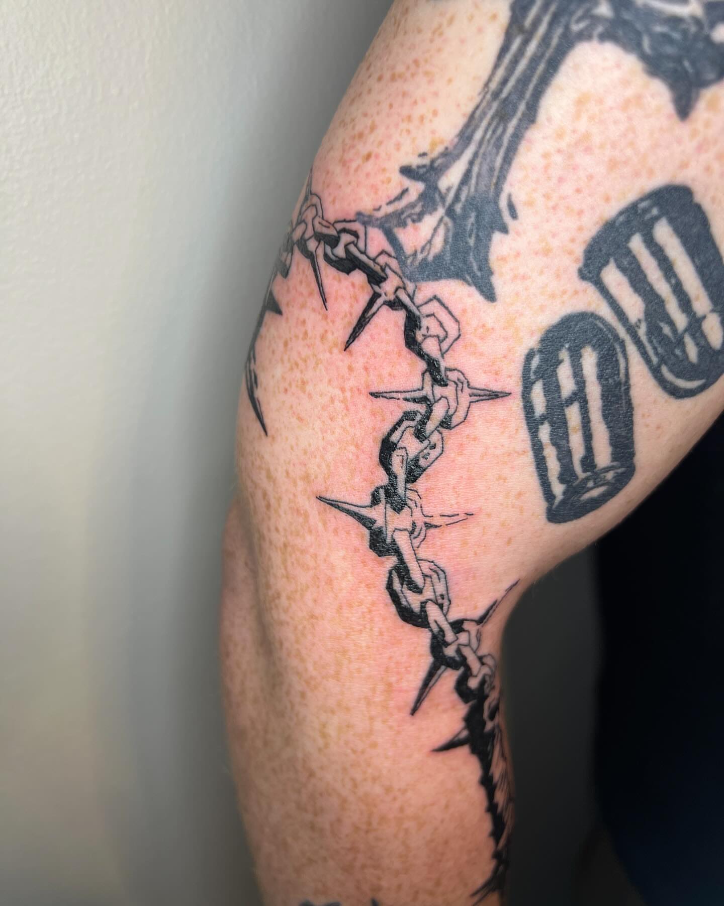 Barbed chain black and grey tattoo on the forearm by Adam
