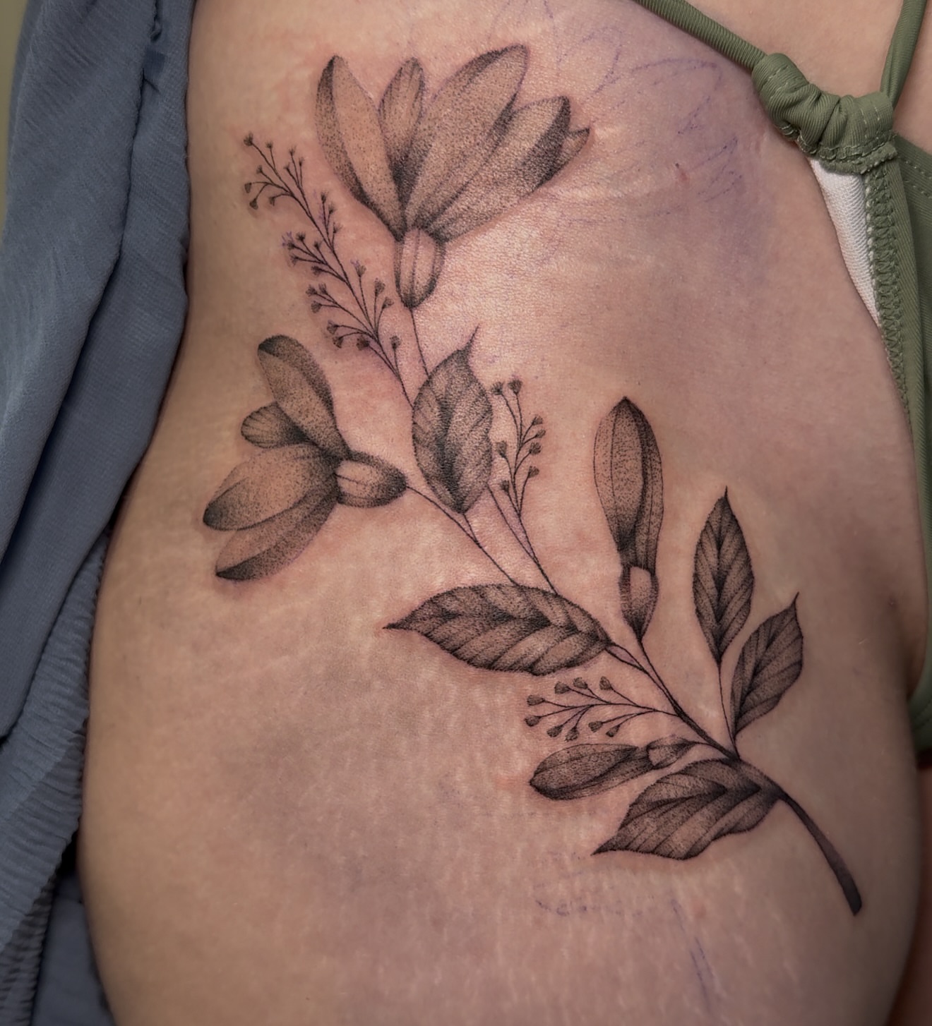 Floral arrangement black and grey tattoo on the ribs by Tattoo Artist