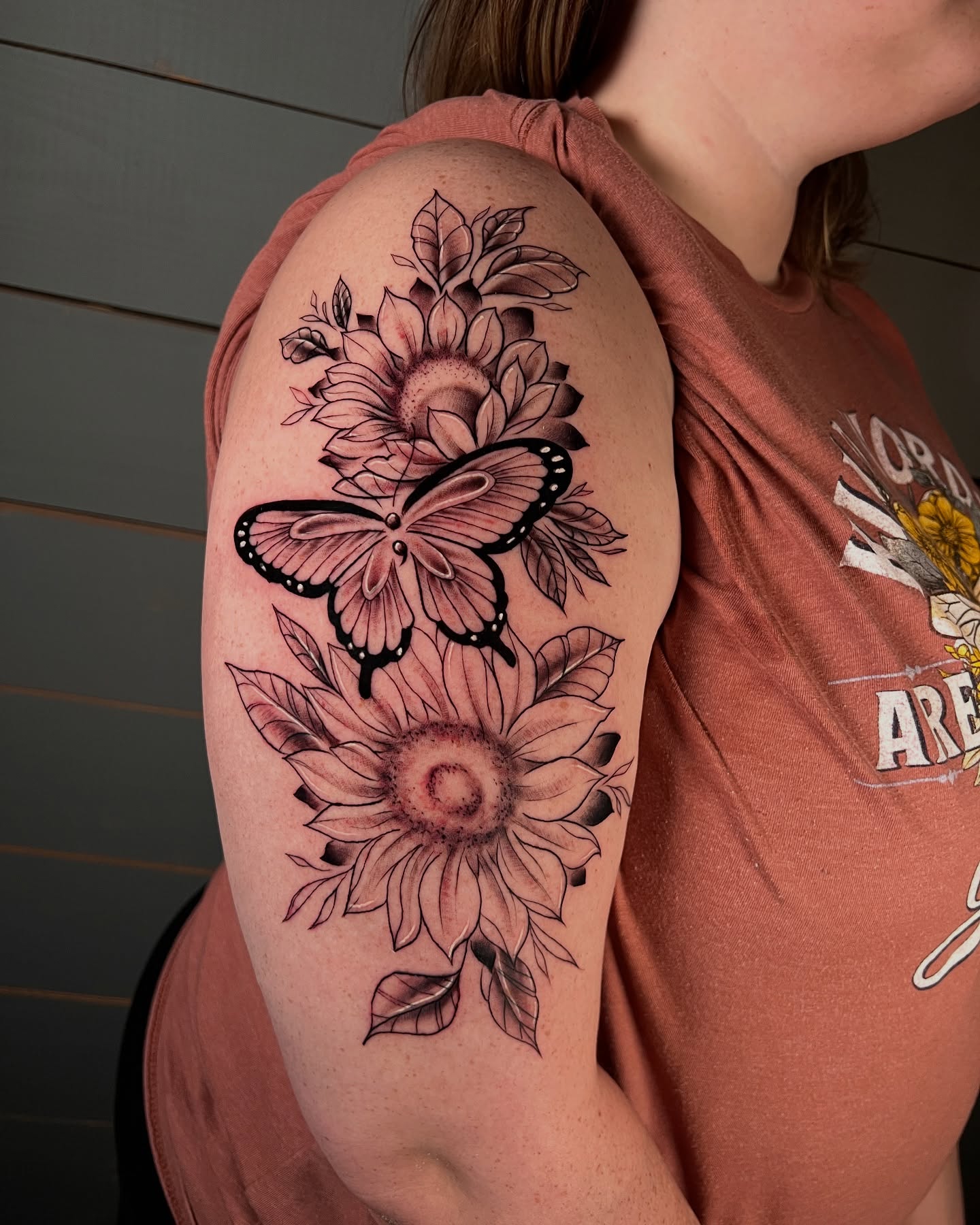 Sunflower and butterfly black and grey tattoo on the upper arm by Tattoo & Body Artist, Gastonia, North Carolina