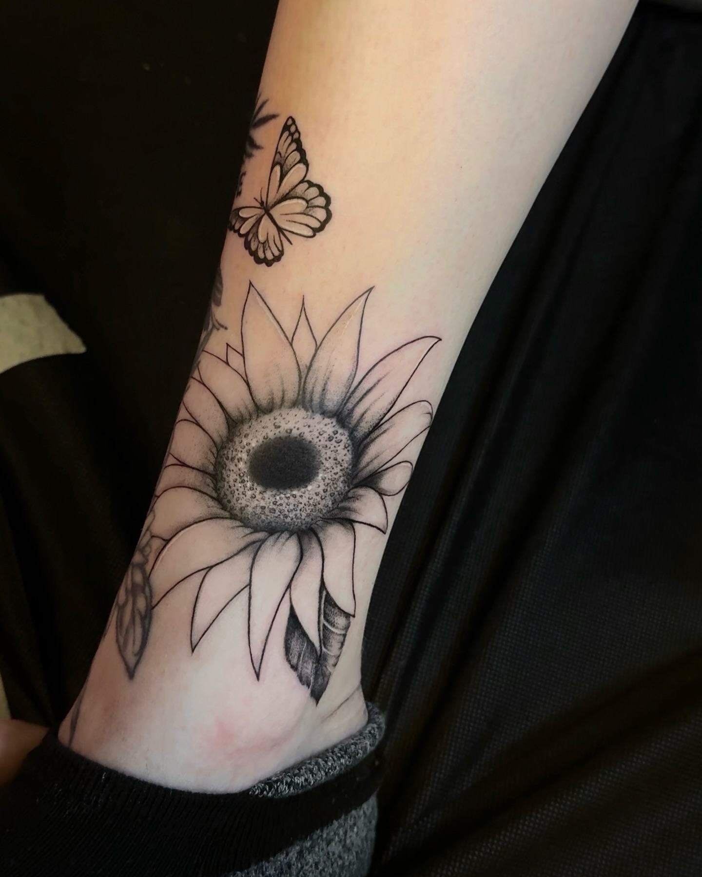 Sunflower and butterfly black and grey tattoo on the forearm by Kris Tattoo Chicago