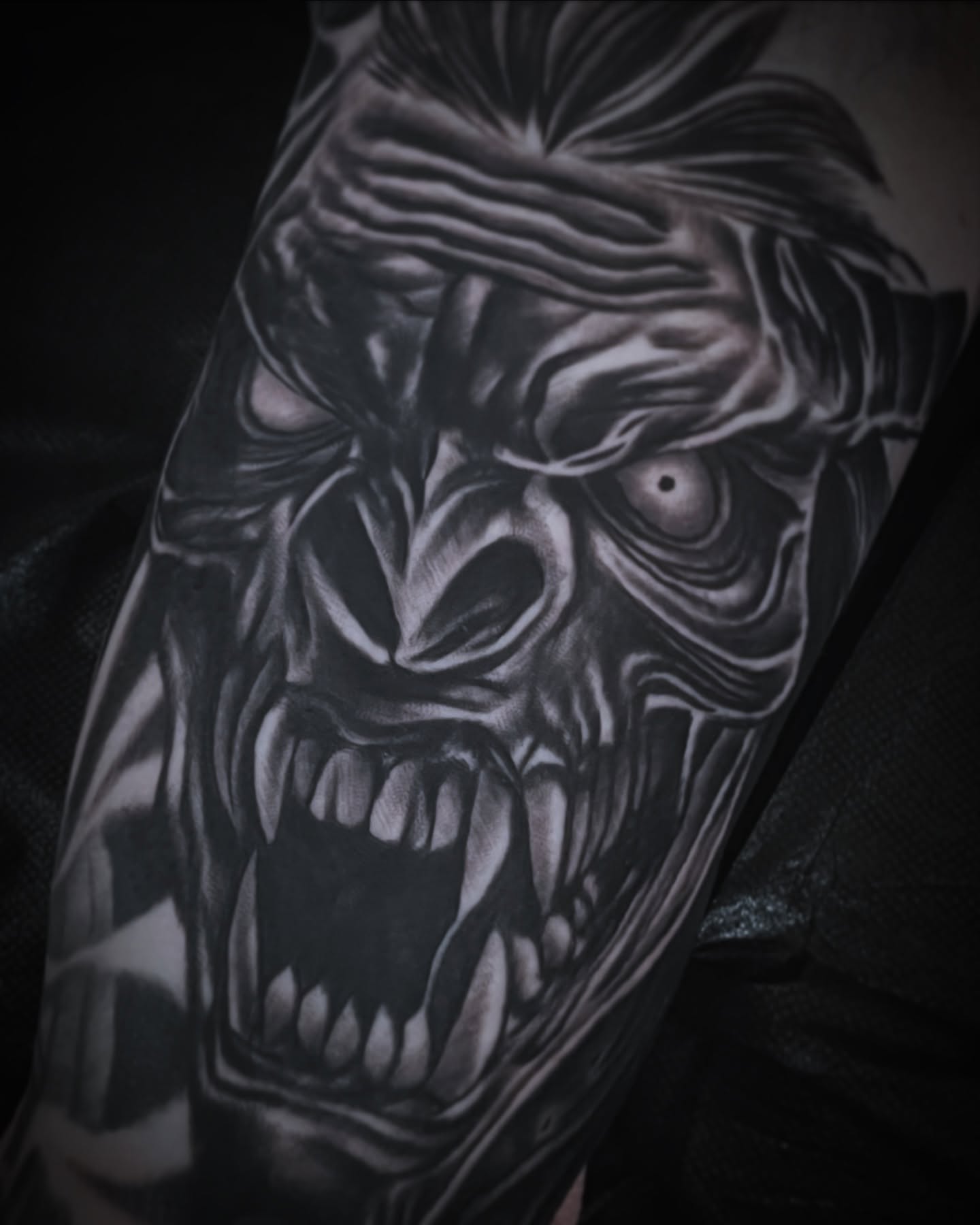 Demon face dark realism tattoo on the forearm by Frank Mostek