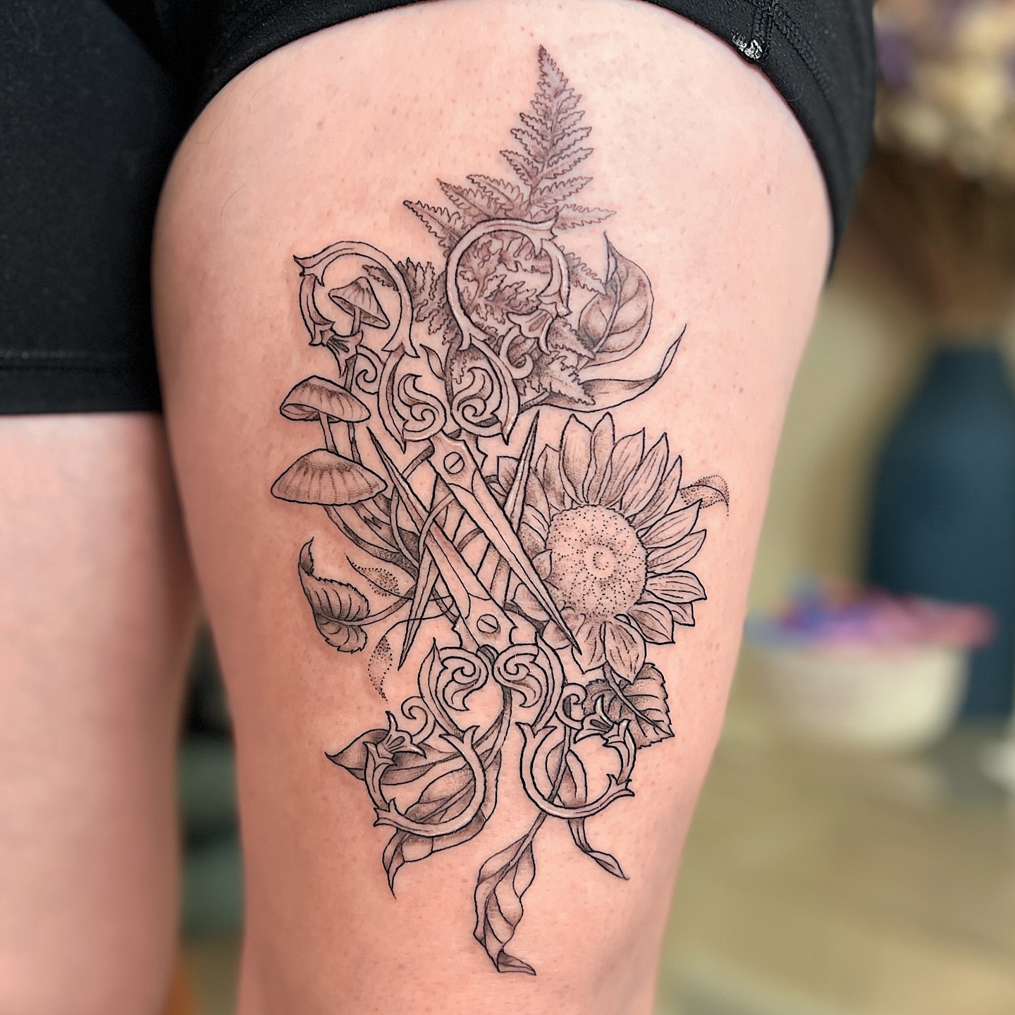 Sunflower and scissors black and grey tattoo on the thigh by Kelsi Hooper, Seattle, Washington