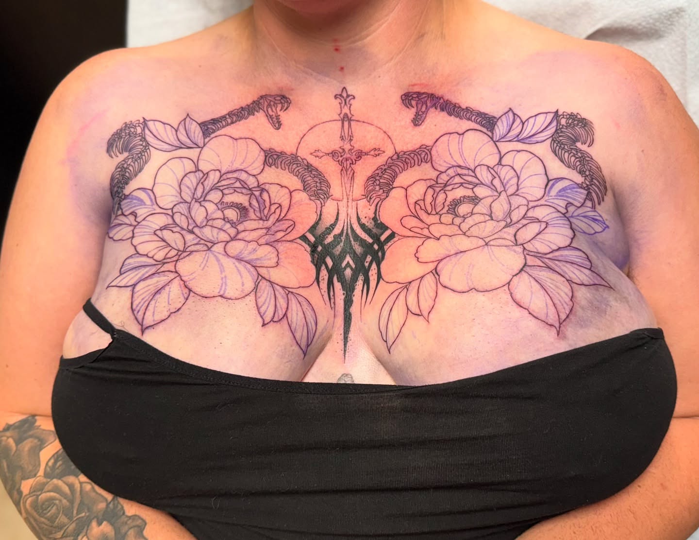 Peony and cross black and grey tattoo on the chest by Tattoo Artist