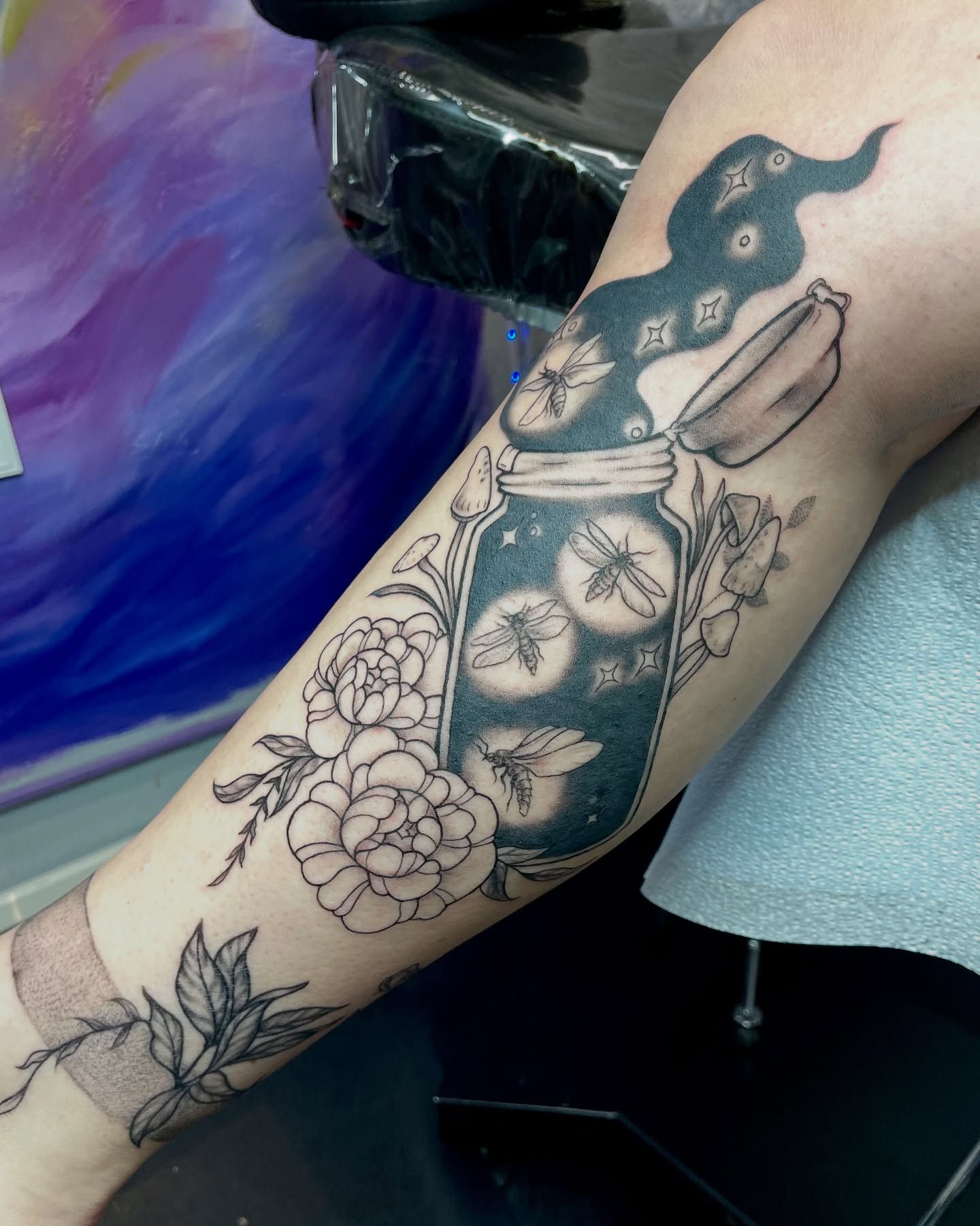 Mason jar with flowers and bees black and grey tattoo on the forearm by Christin Baumgart