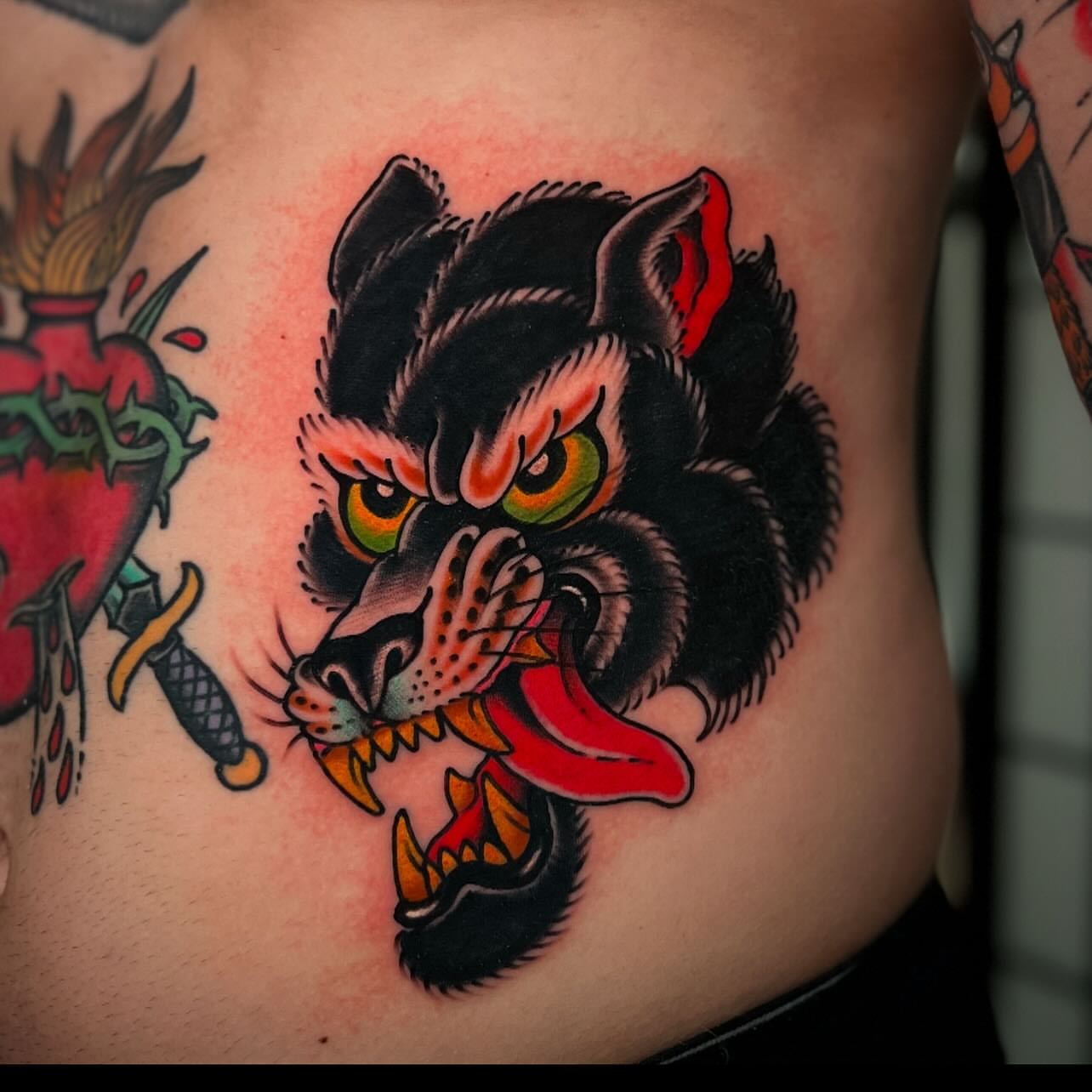 Wolf head American traditional tattoo on the ribs by Chris Romolini