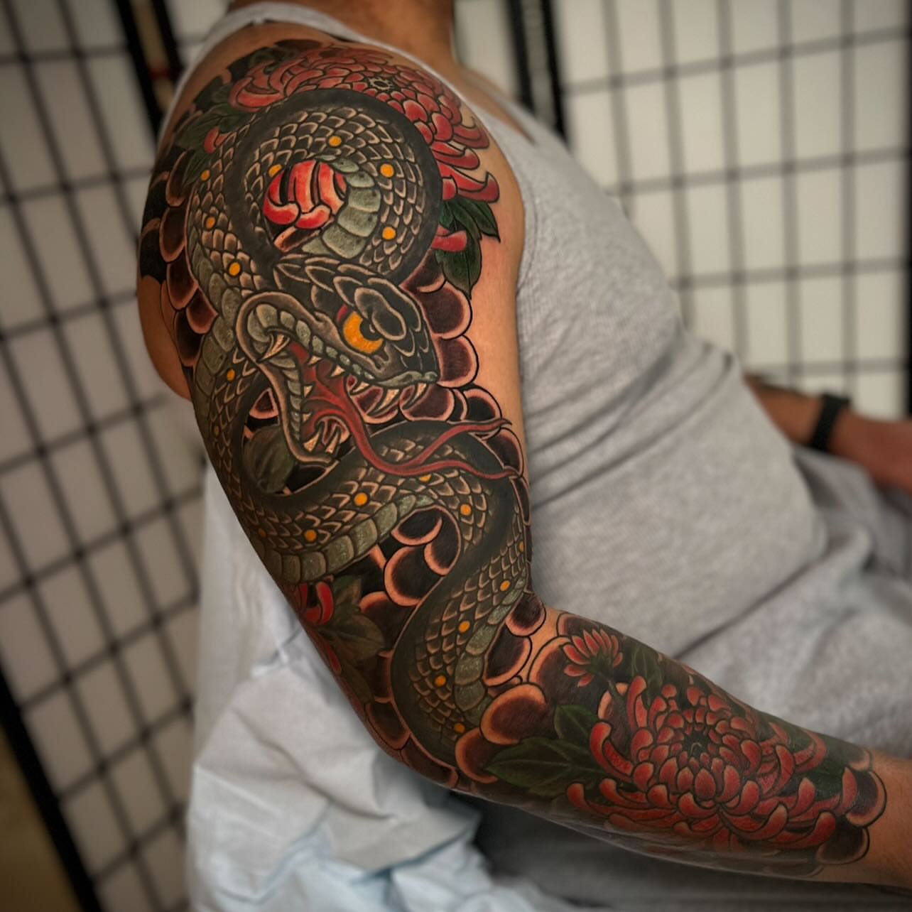 Snake and chrysanthemum japanese irezumi tattoo on the upper arm by Chris Romolini