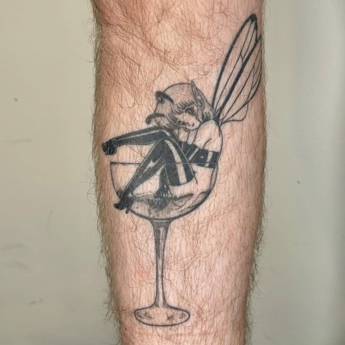 Fairy in martini glass black and grey tattoo on the forearm by taline