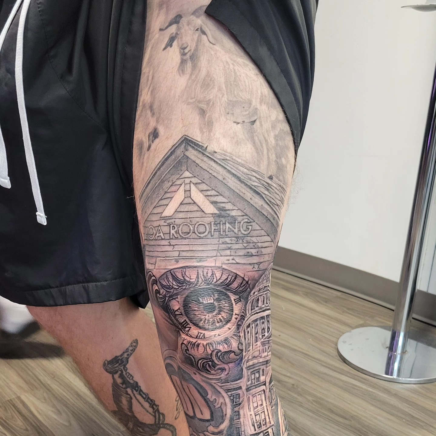 Roofing company logo black and grey tattoo on the thigh by Beto Tats, Round Rock, Texas