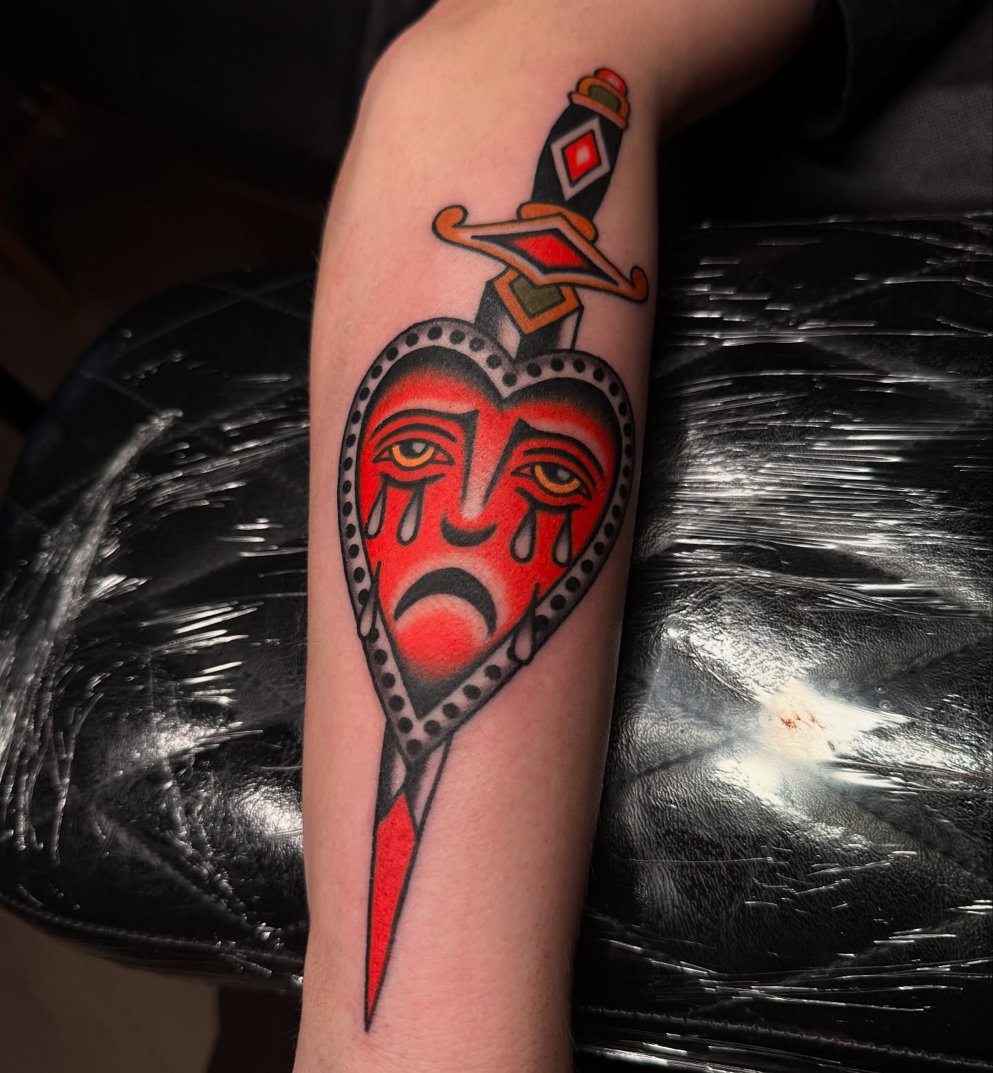 Heart with crying face American traditional tattoo on the forearm by Chaz Otto