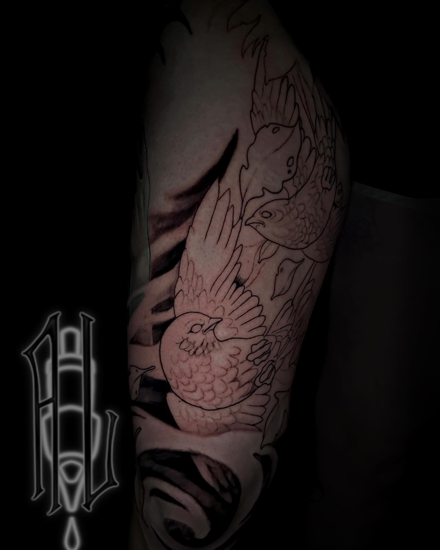 Bird and fish black and grey tattoo on the upper arm by Andrew Luce