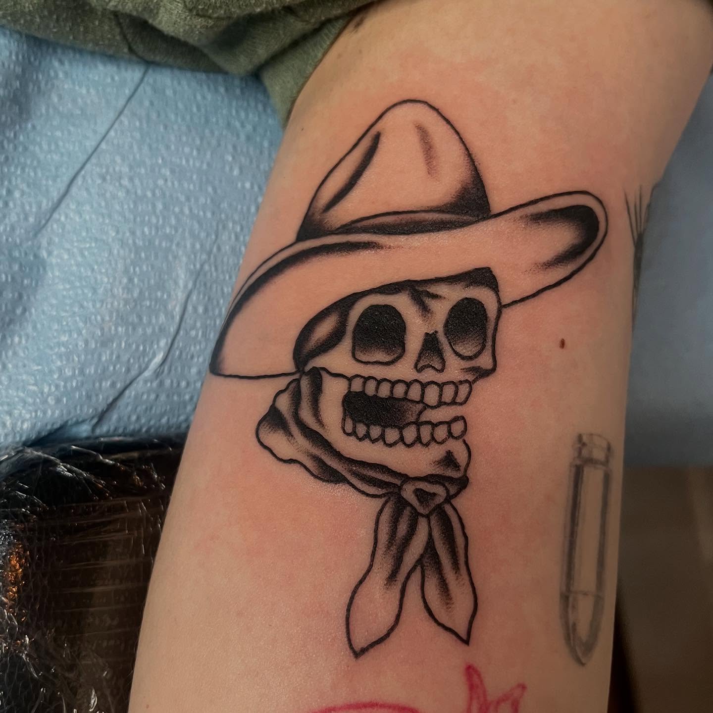 Skull wearing hat black and grey tattoo on the forearm by Mariah Nguyen