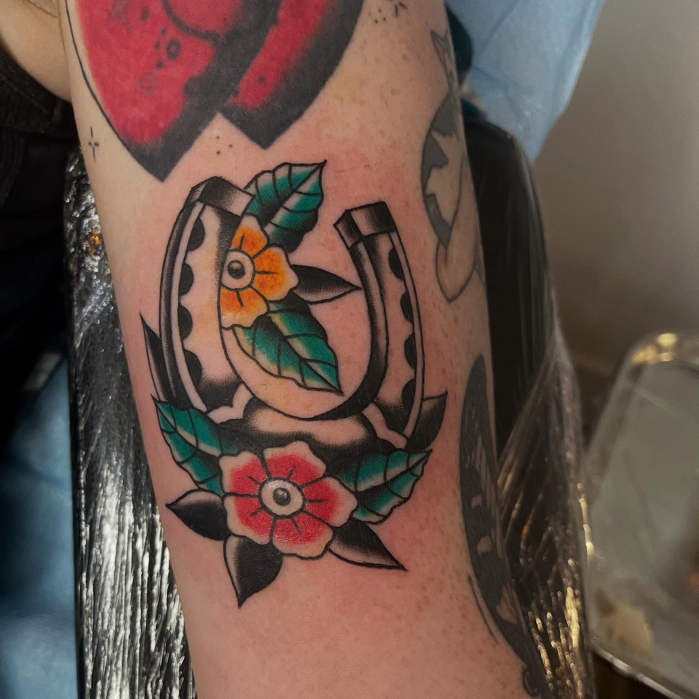 Horseshoe and flowers American traditional tattoo on the forearm by Mariah Nguyen