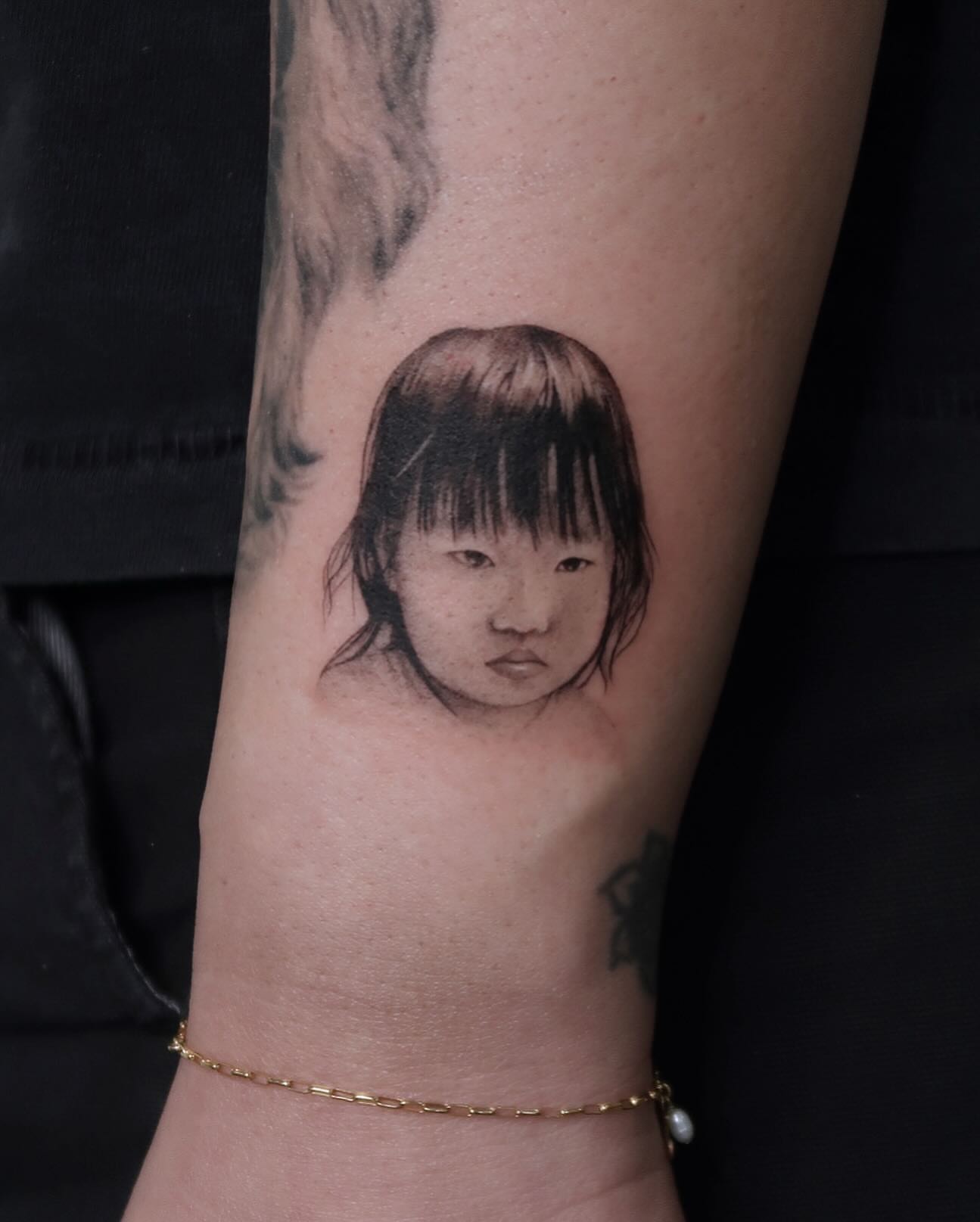 Child portrait realism tattoo on the forearm by Alissa Jung
