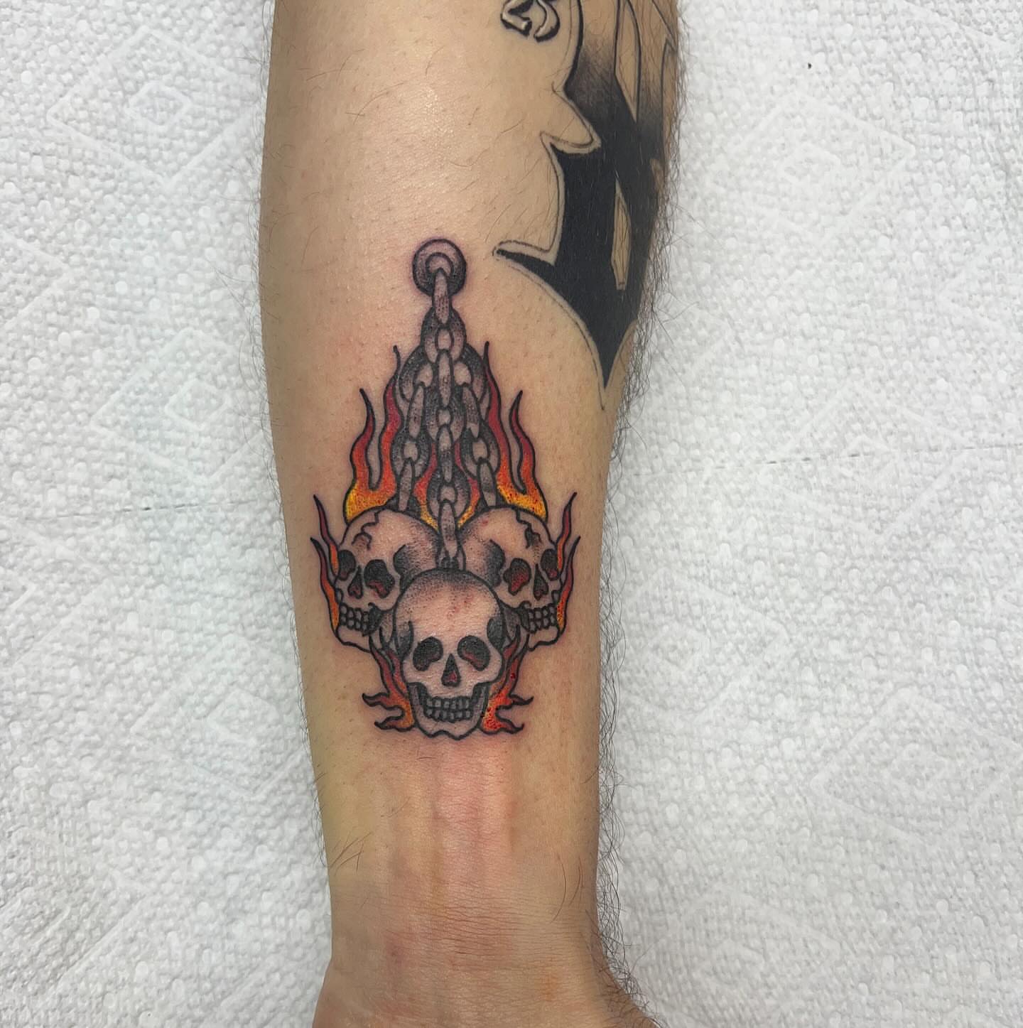 Flaming skulls American traditional tattoo on the forearm by Katie Sayre