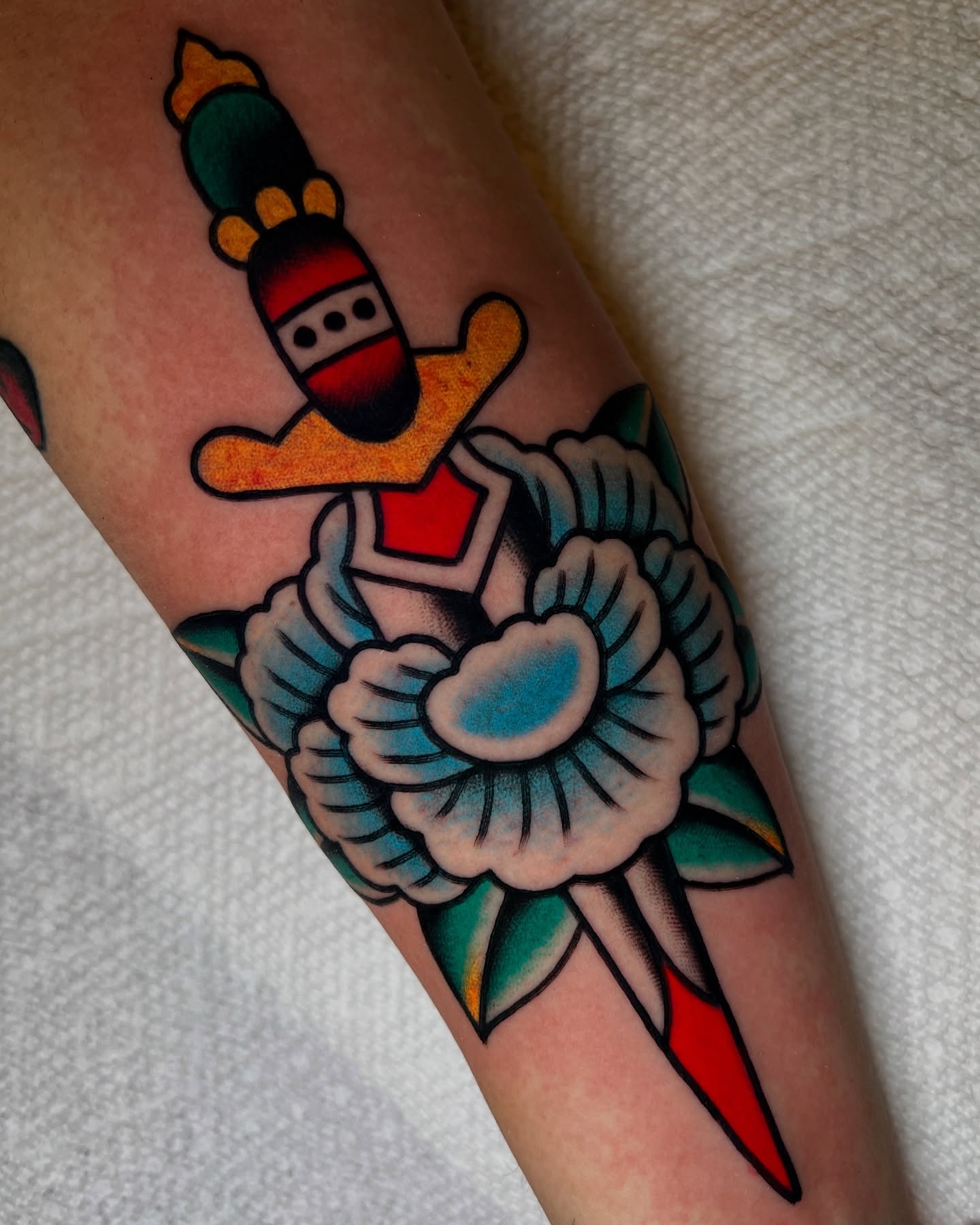 Rocket and flower American traditional tattoo on the forearm by Ian Jett