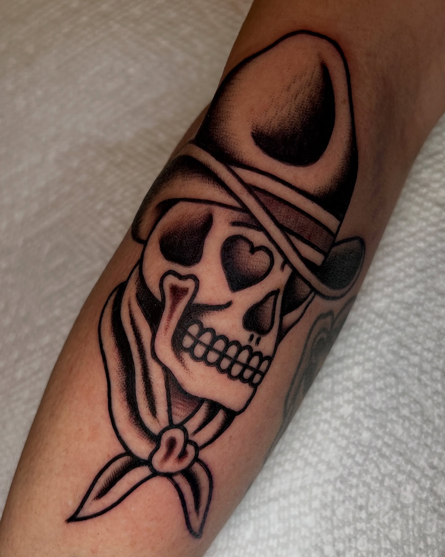 Skull with bandana American traditional tattoo on the forearm by Ian Jett