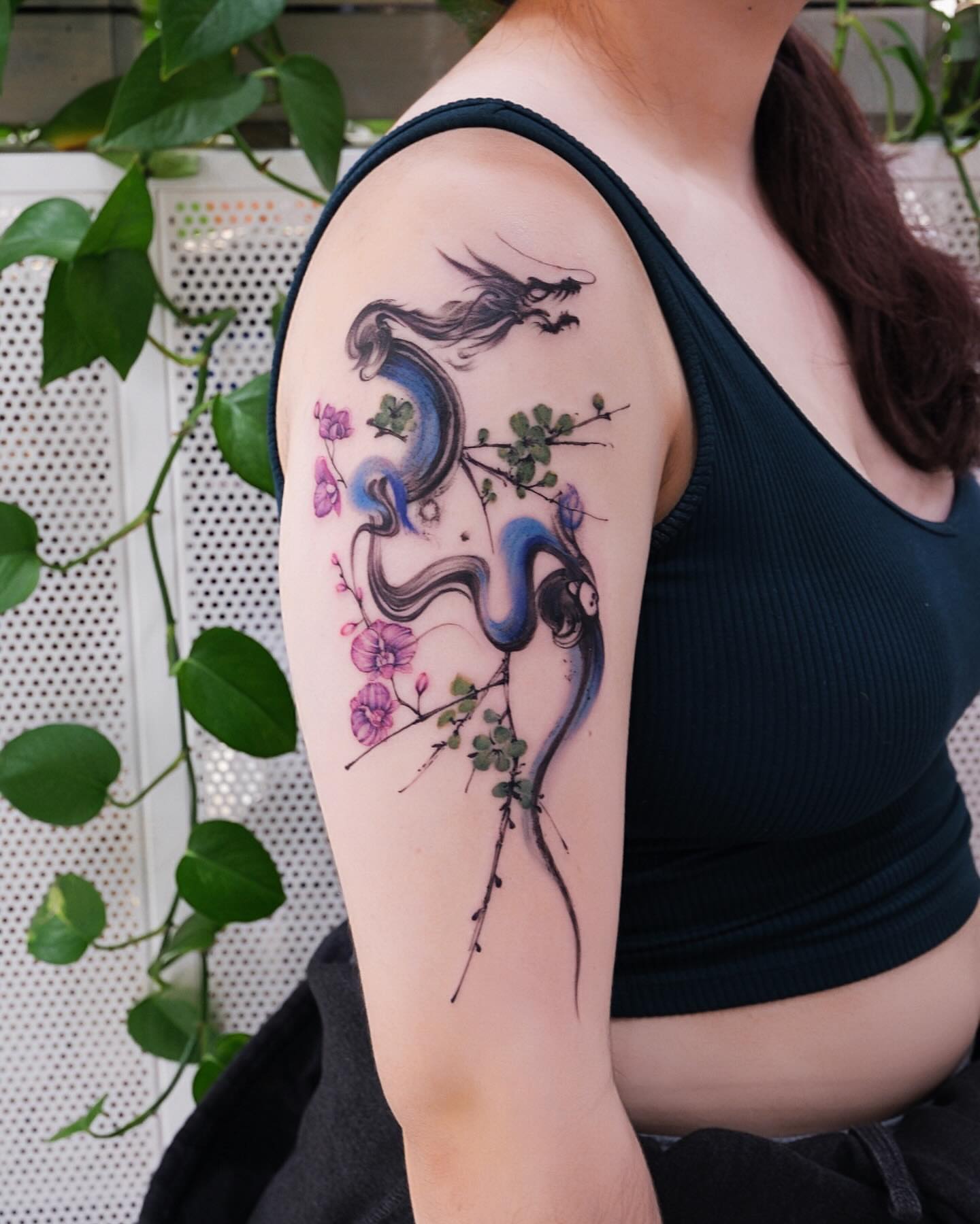 Dragon and flowers watercolor tattoo on the upper arm by MJ tattooist