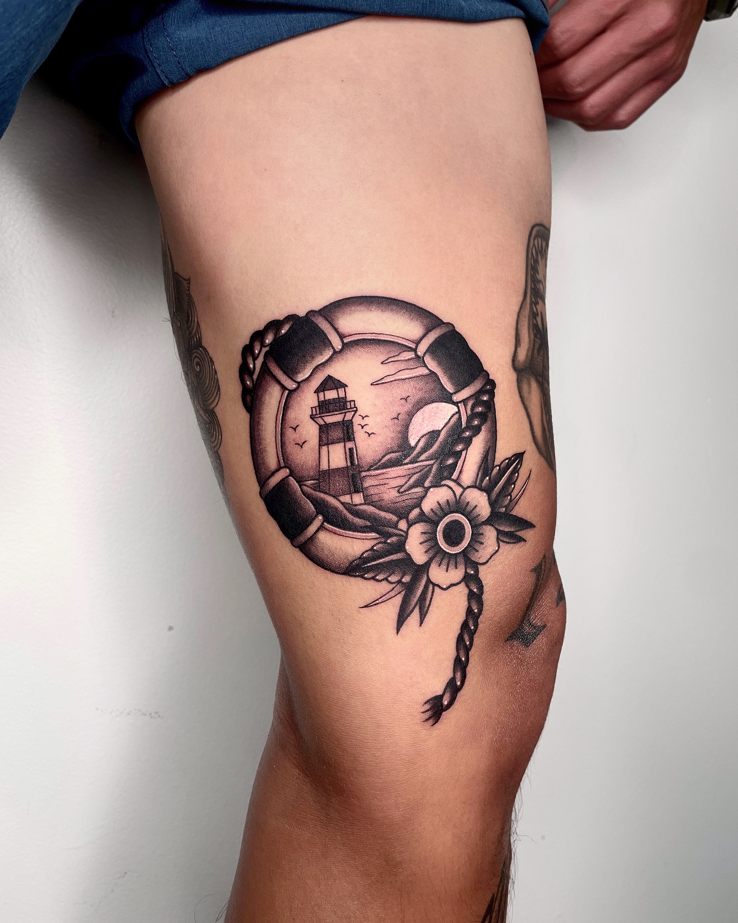 Lighthouse and life preserver American traditional tattoo on the thigh by LA tattoo