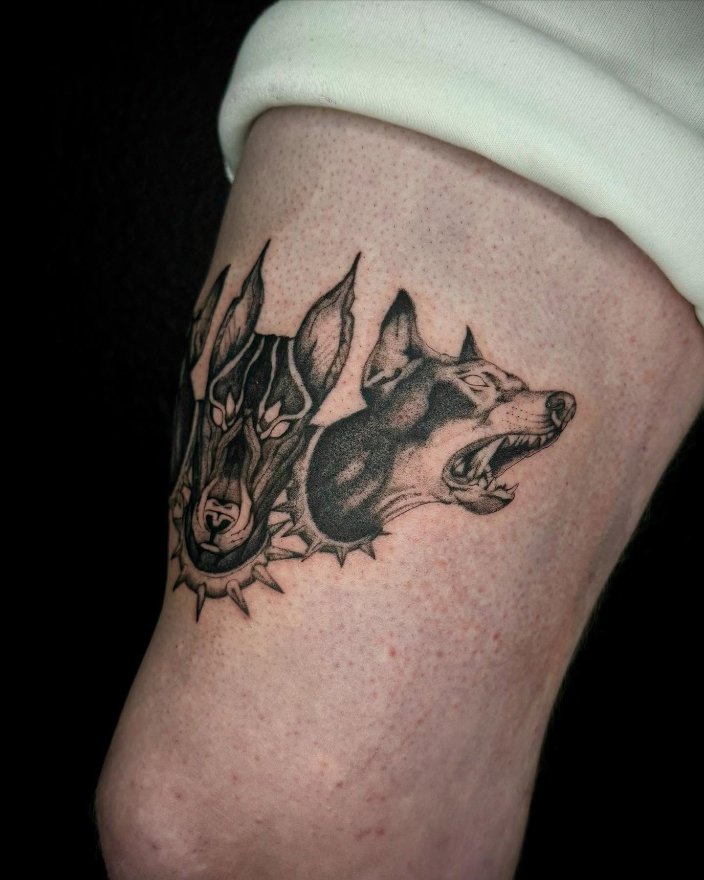 Wolf heads black and grey tattoo on the thigh by Chino