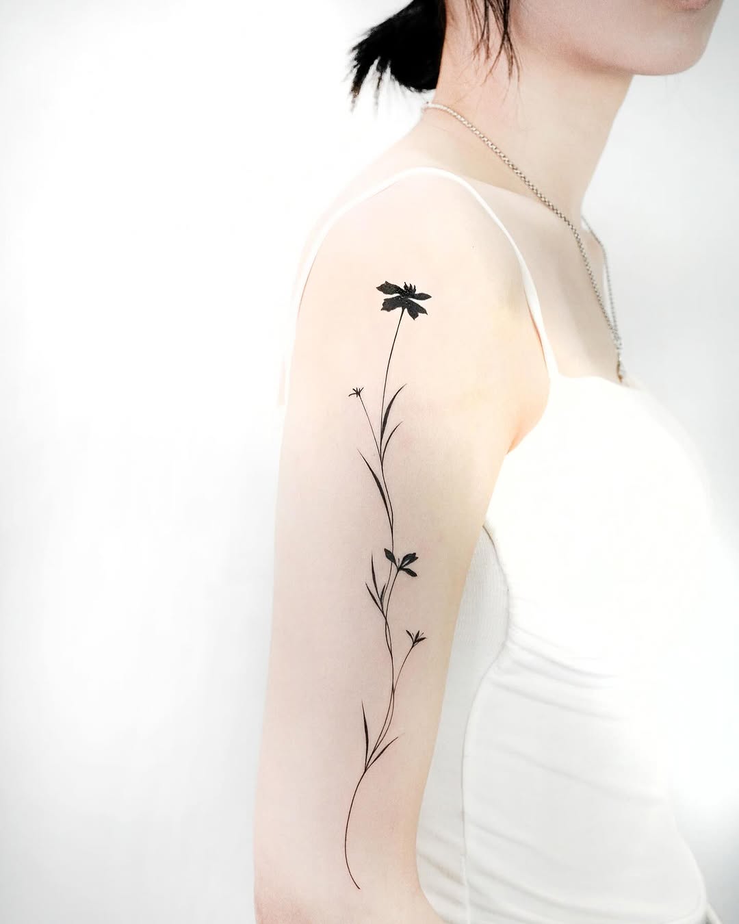 Single flower stem blackwork tattoo on the forearm by 초현실과 현실 그 사이를 그리다.