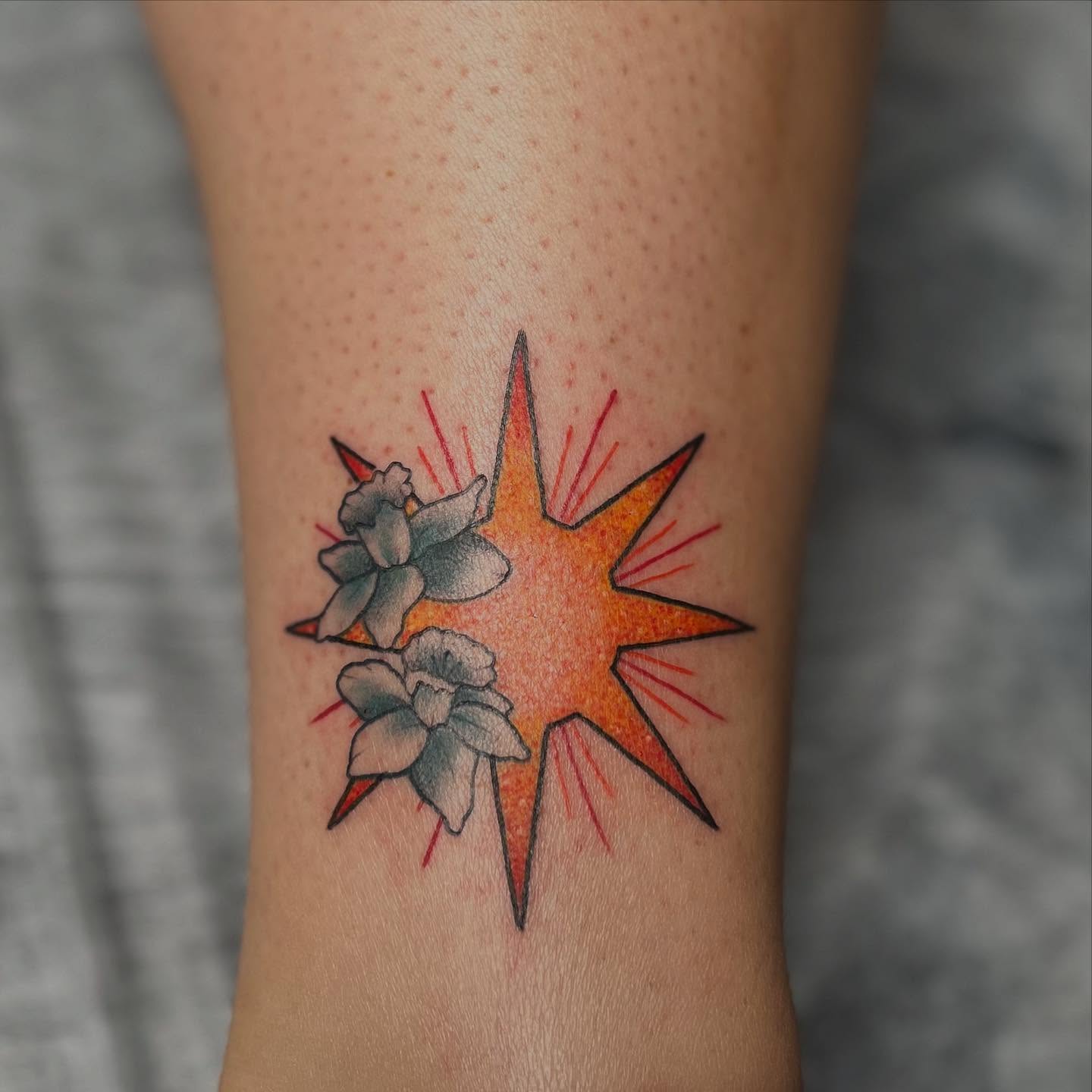 Starburst with flowers American traditional tattoo on the forearm by Lexi Ross