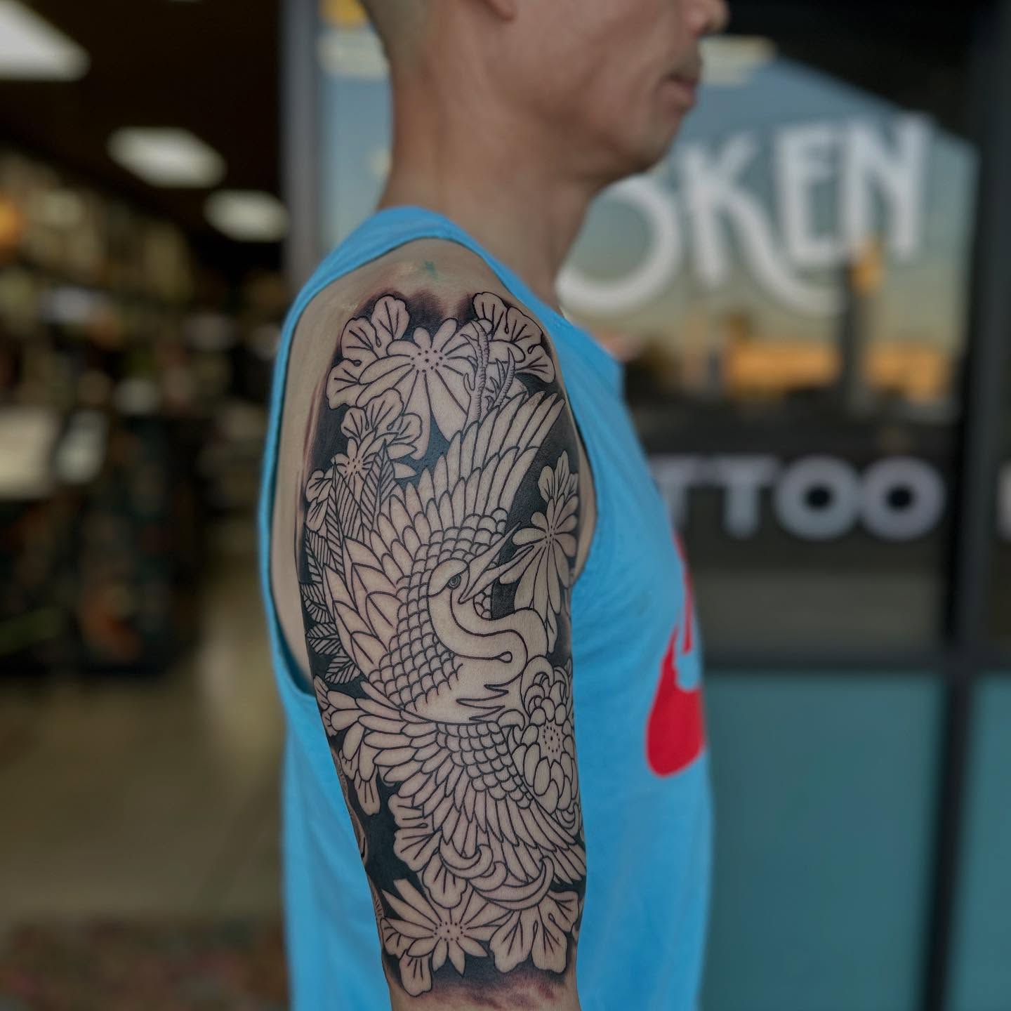 Floral bird black and grey tattoo on the upper arm by Shawn Feng