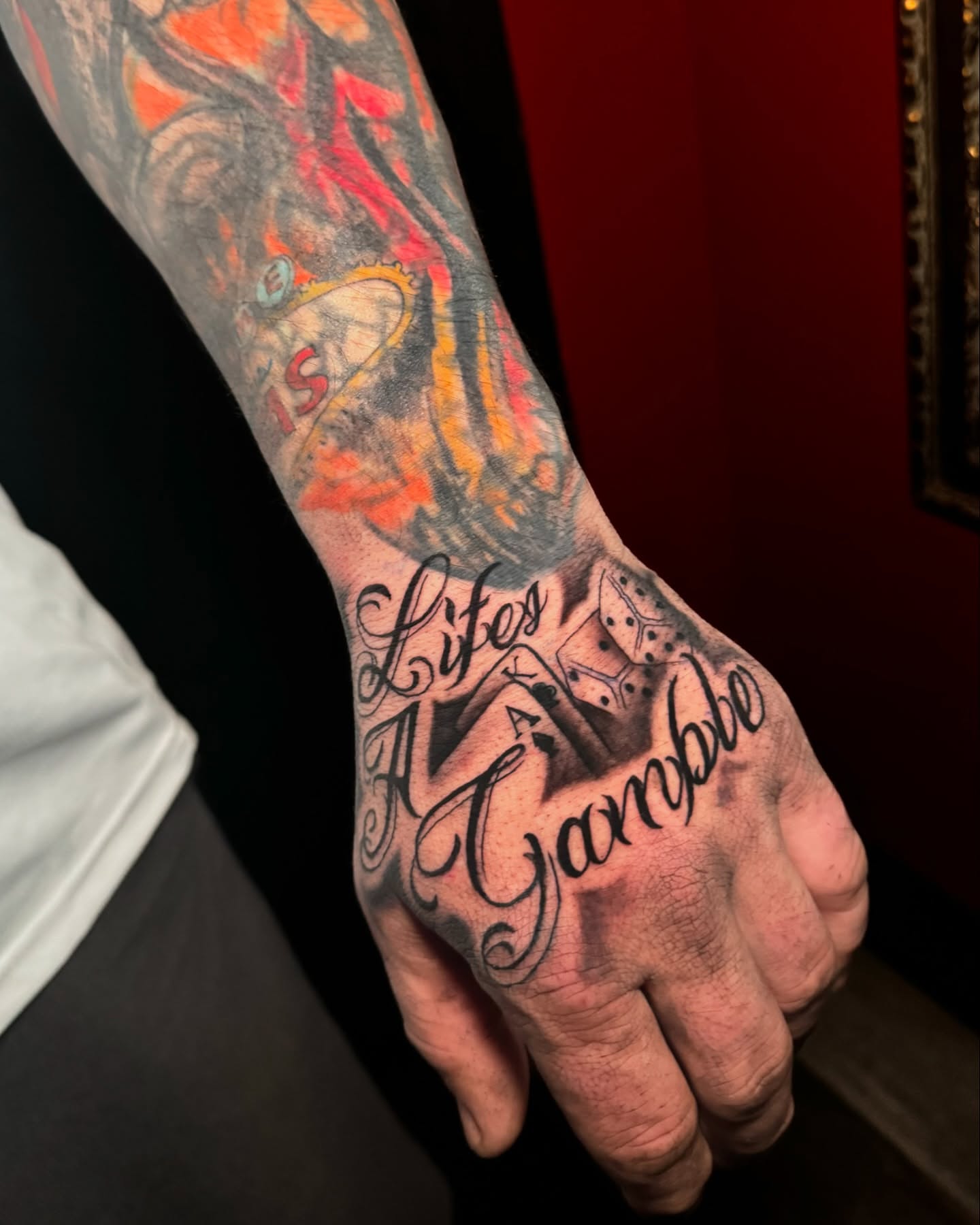 Dice and script lettering script tattoo on the hand by Ryland - Tattoo Artist