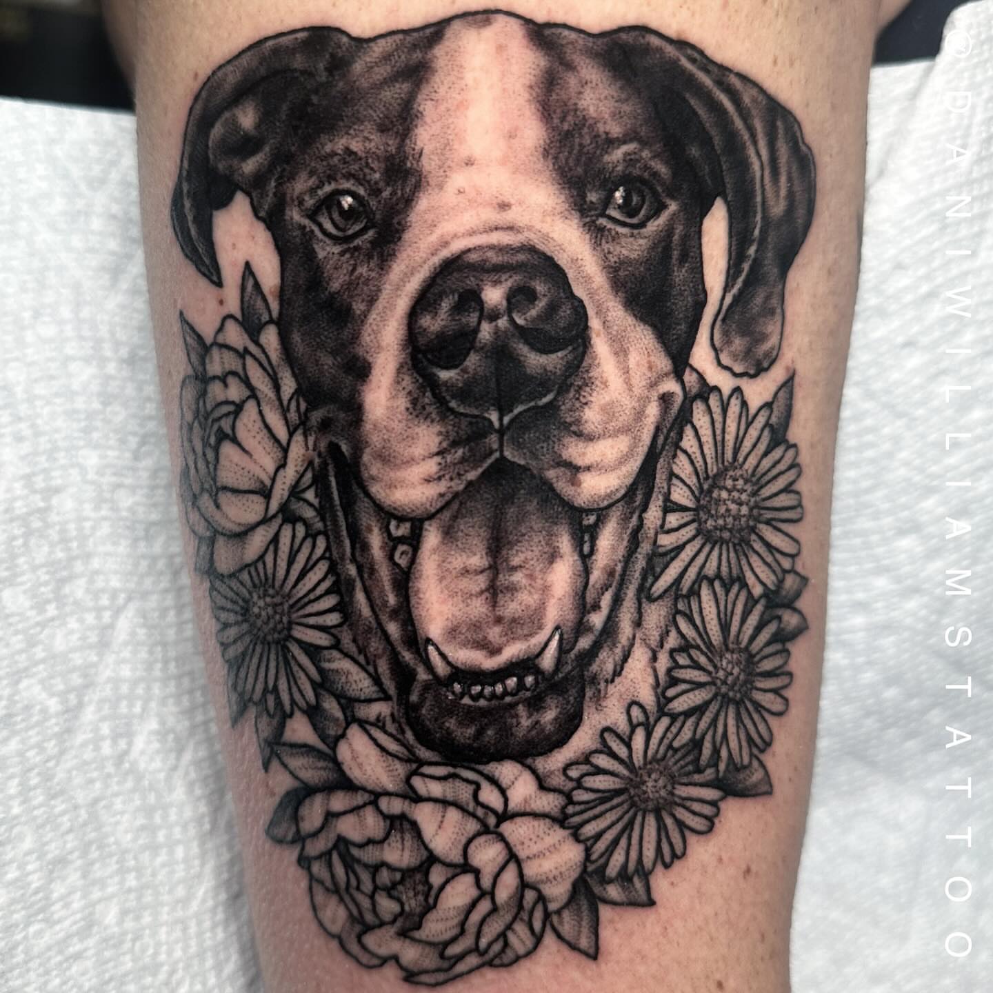 Dog with flowers realism tattoo on the forearm by Dani Johnson