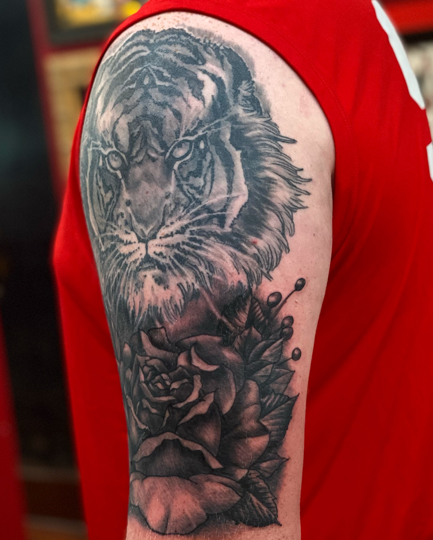 Lion and roses realism tattoo on the upper arm by Christopher Sanders