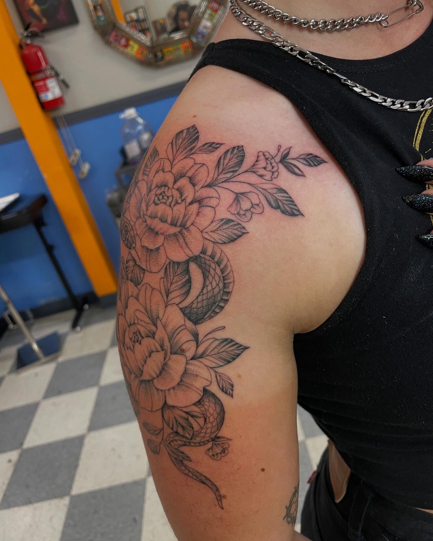 Snake and peony black and grey tattoo on the upper arm by Manny