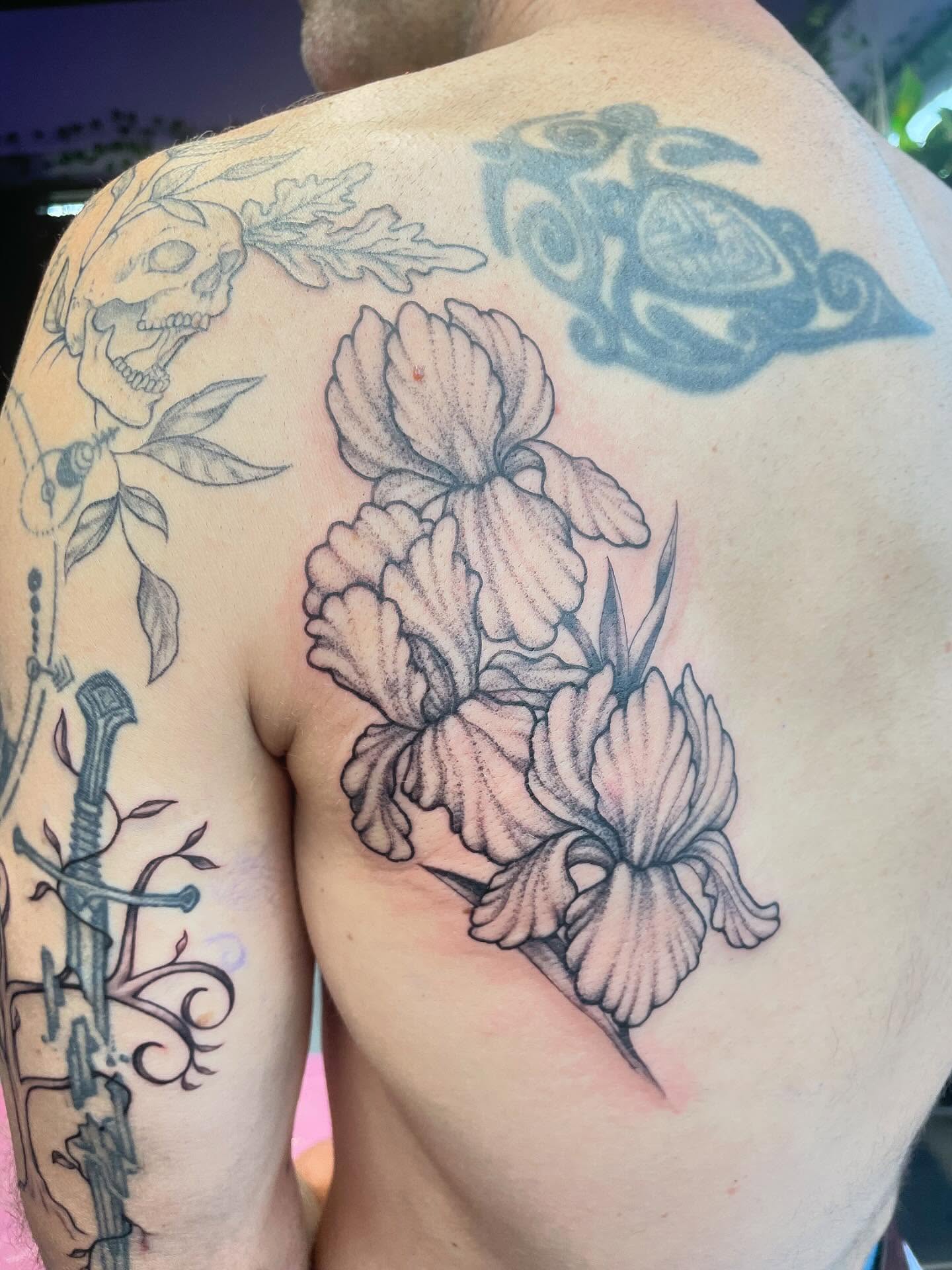Iris flowers black and grey tattoo on the shoulder by Christin Baumgart