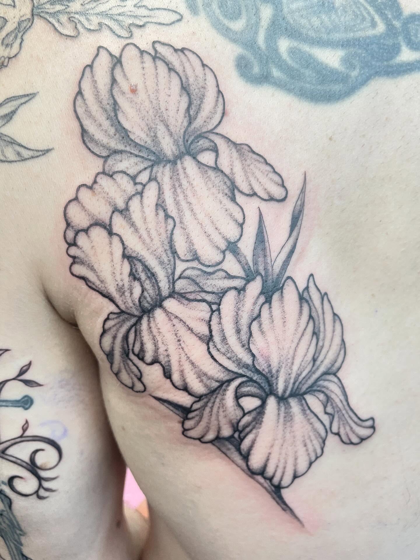 Iris flowers black and grey tattoo on the chest by Christin Baumgart