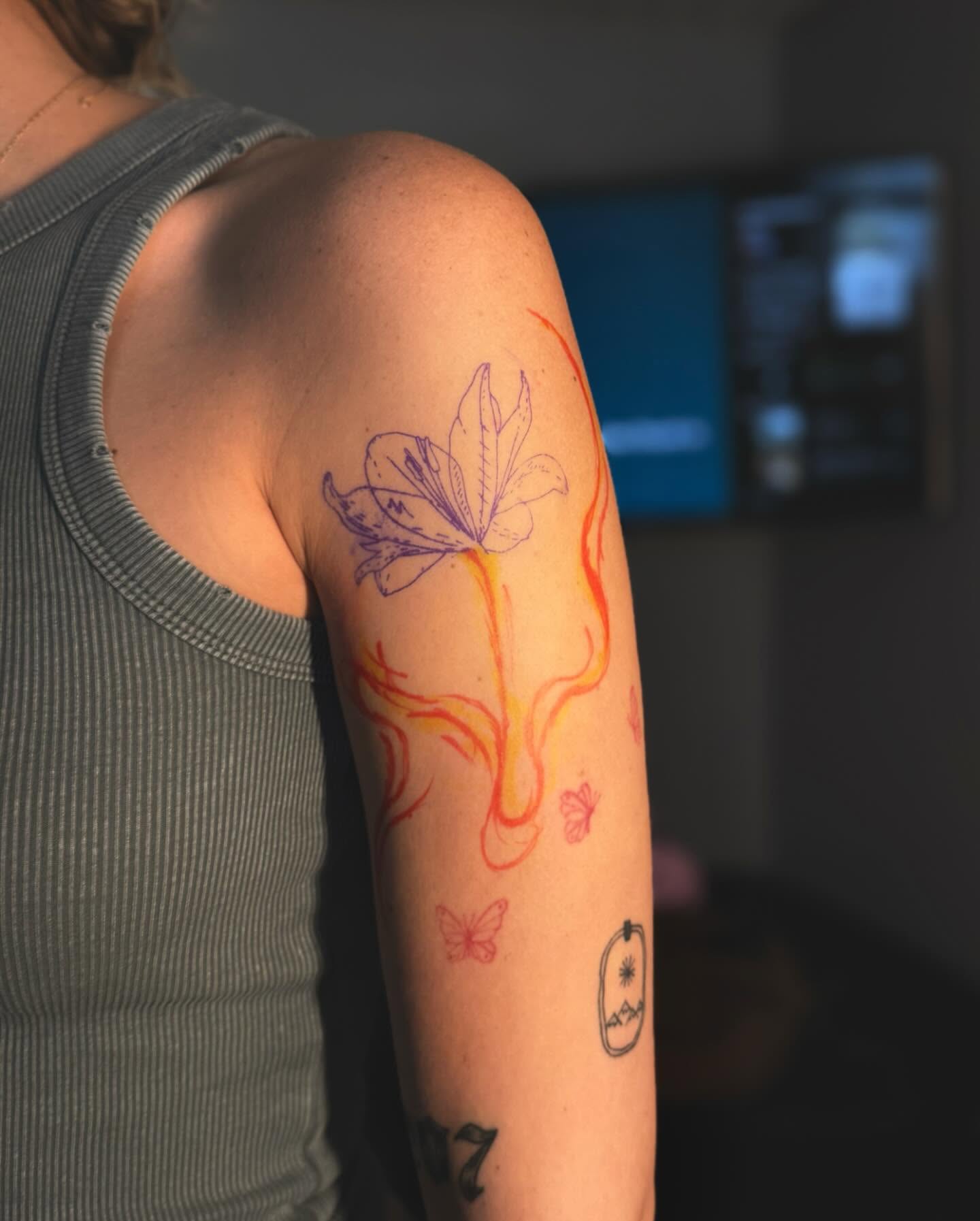 Flame lily new school tattoo on the upper arm by laura baldwin