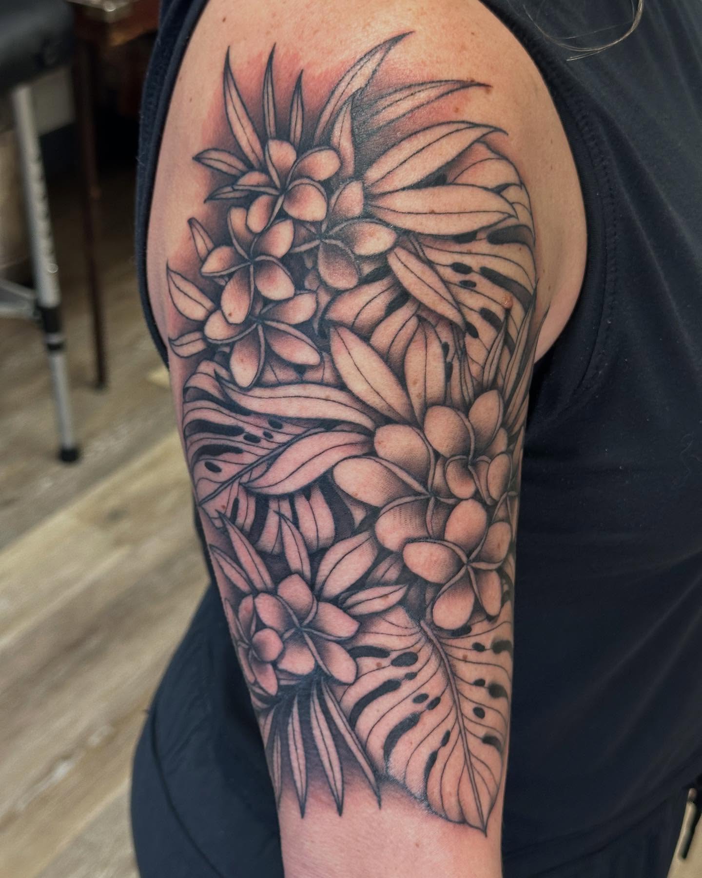 Plumeria flowers black and grey tattoo on the upper arm by Classy Fucking Lady Tattooer